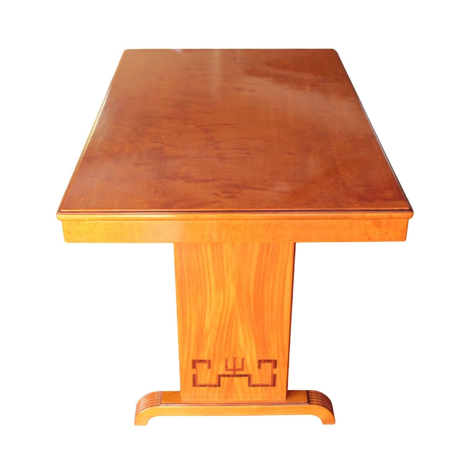 Versatile table in flame birch having a rectngular top with accented molding resting on a pair of rectangular panel pedestals in book-matched elm decorated with stylized meander inlays in palisander and rosewood. Raised on a pair of 