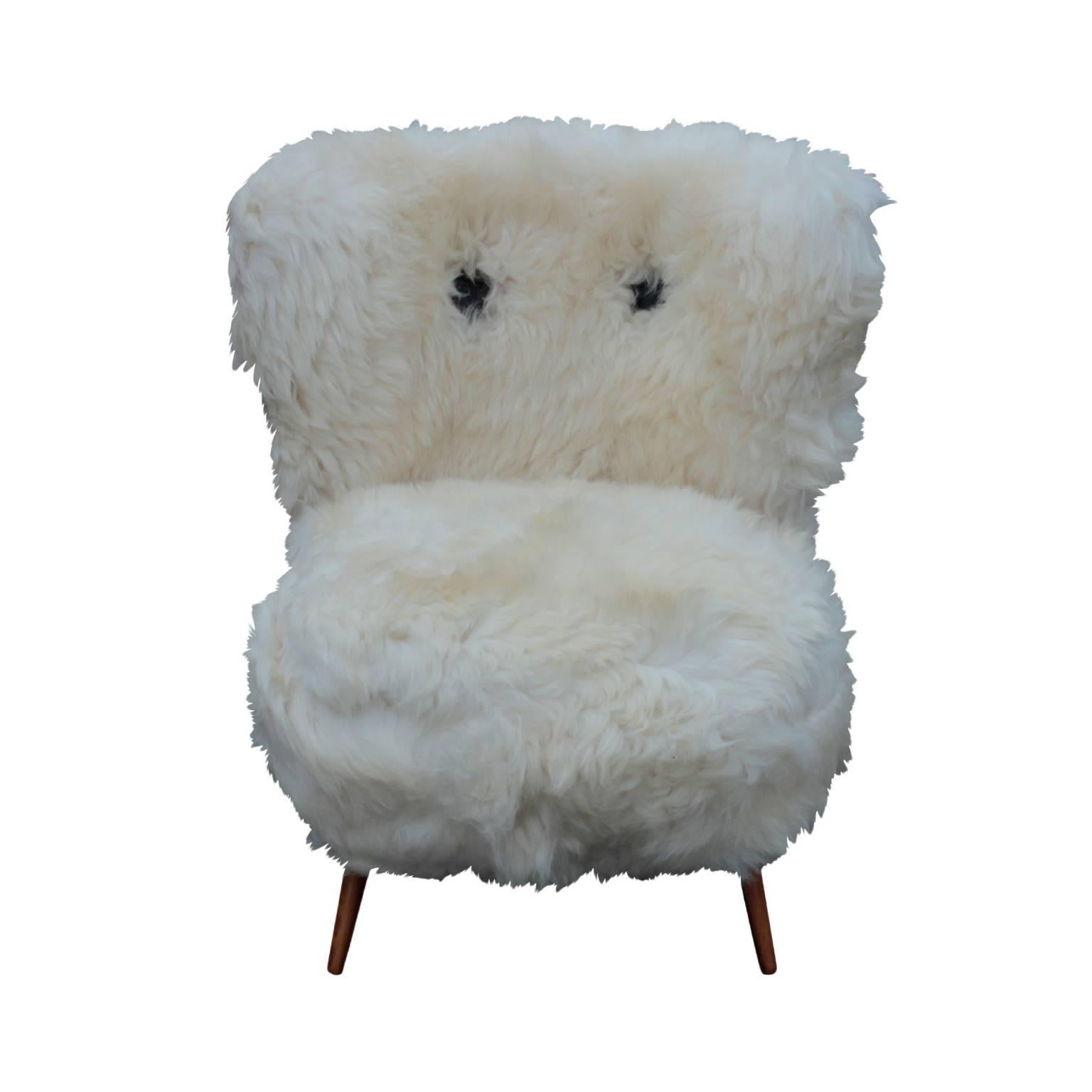 Newly covered with sheepskin, featuring two black leather buttons on the backrest and four splayed conical legs in beech.