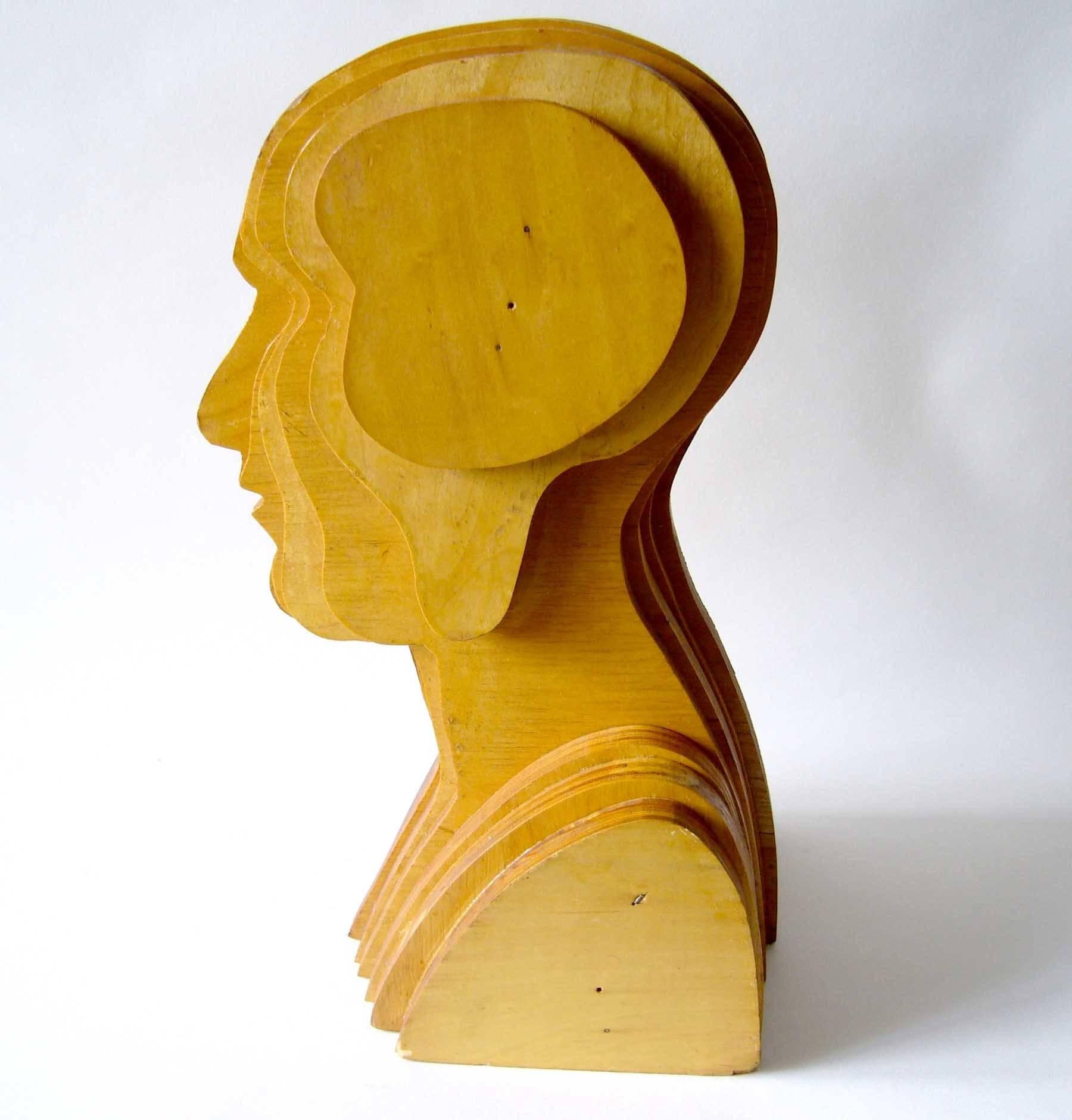 Laminated plywood unconventional head sculpture, circa 1974. Sculpture is reminiscent of works by Ernest Trova of the same period. Piece measures 16" x 9"x 8" and is signed beneath Approved 8-28-74, Display. In good vintage condition