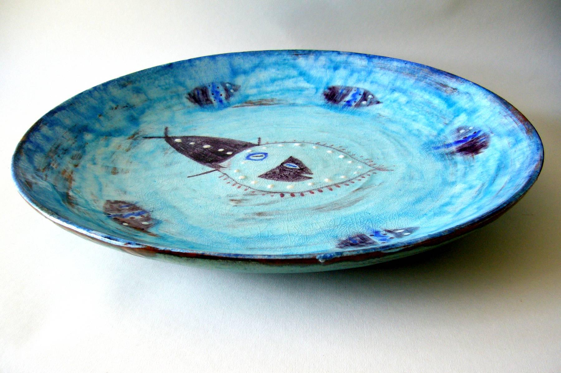 Large-scale ceramic charger with fish motif swimming in an ocean water field. Note the raised white dot embellishment on the fish at centre. Charger measures 16.5