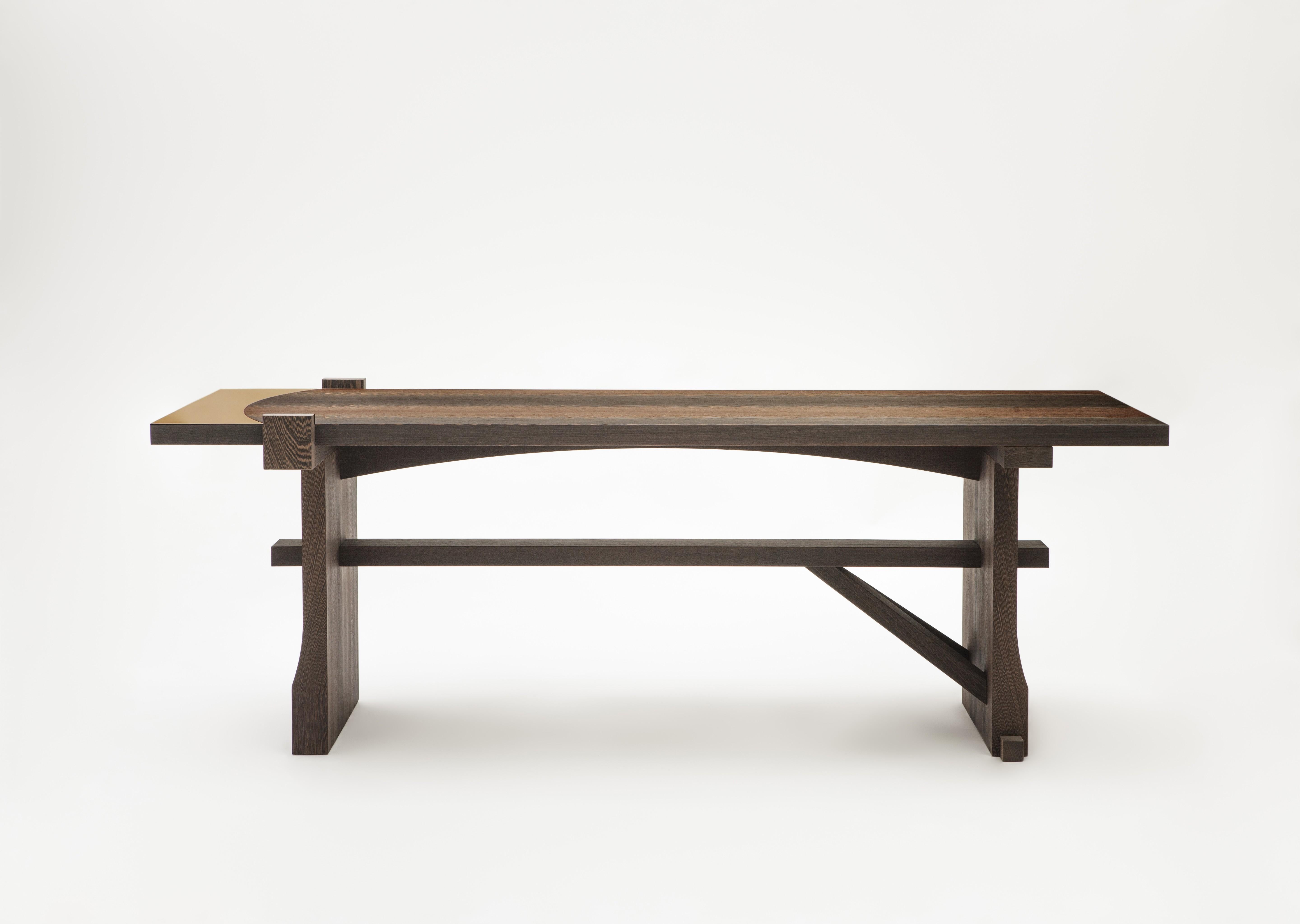 Fratino è realizzato in wengè. la superficie in legno è decorata con un inserto in bronzo che conferisce un tocco di luce preziosa alla semplicità del pezzo.


