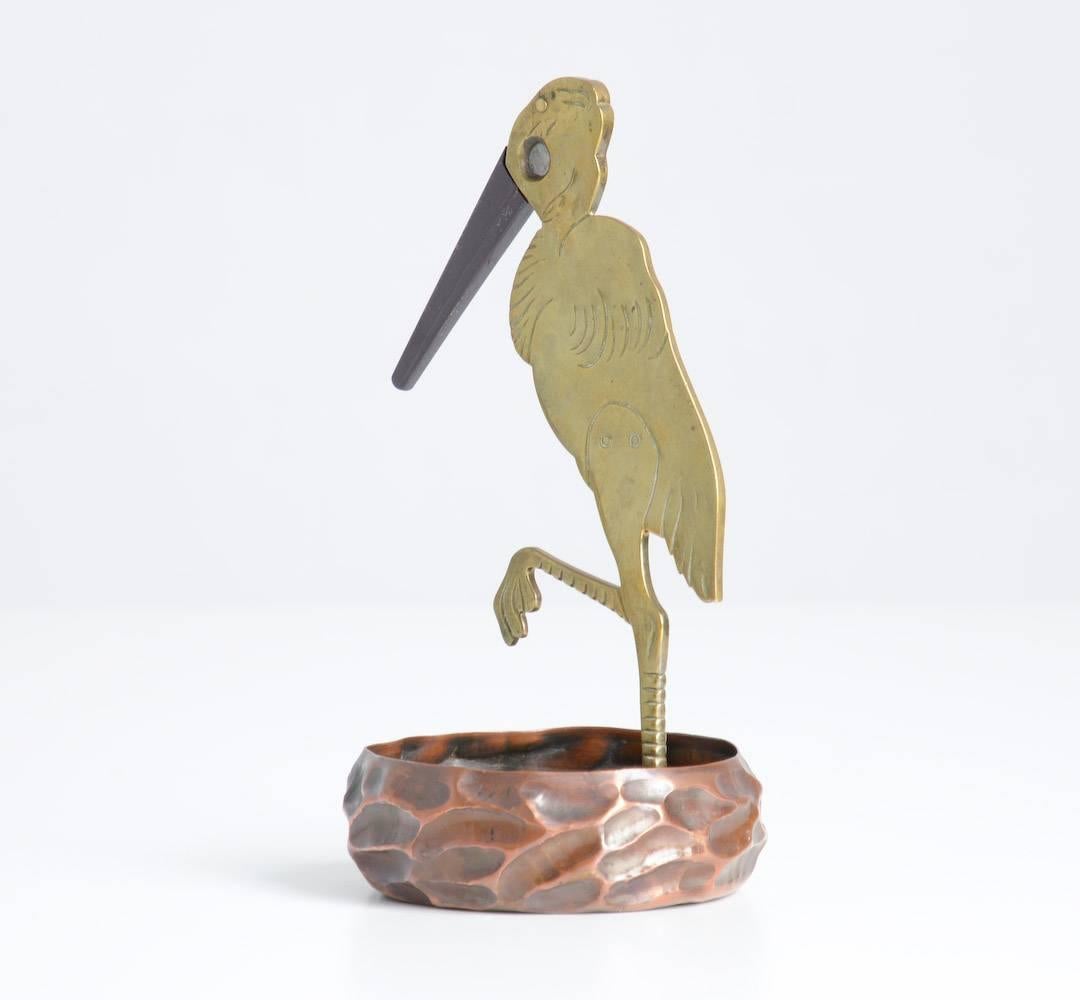 This cigar cutter was designed by the German artist Ignatius Taschner, circa 1905.
You can put a cigar in the eye of the stork when the beak is opened. When you close the beak it will cut the cigar. The cigar tip will fall into the bin in which the