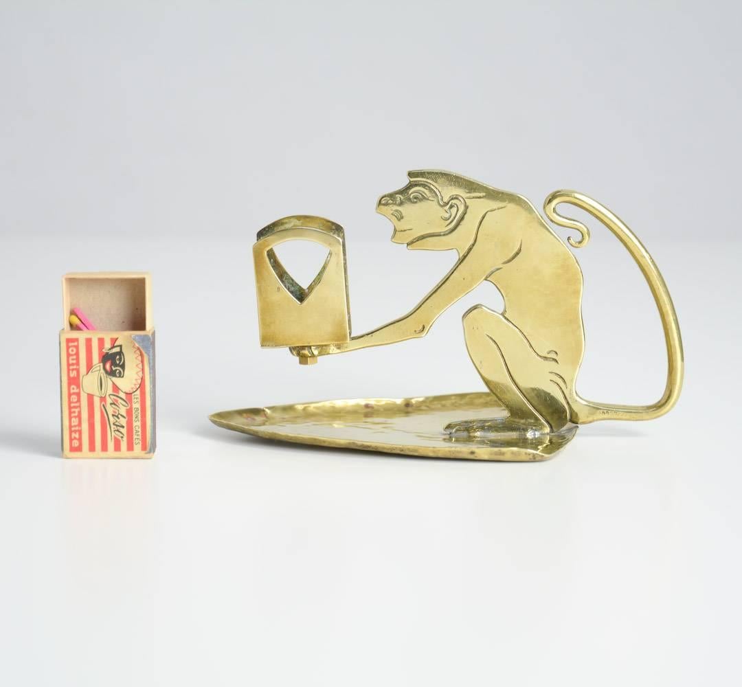 This monkey matchbox holder was designed by the German artist Ignatius Taschner, circa 1905.
The brass monkey, sitting on a triangular plate, holds the matchbox.
This rare matchbox holder is still in very good condition.