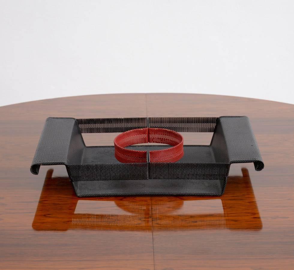 This nice perforated metal serving tray is a great design of the 1950s. It was made in the manner of the work of Mathieu Matégot.
The rectangular black lacquered perforated metal tray with a red circular accent is typical for the design of