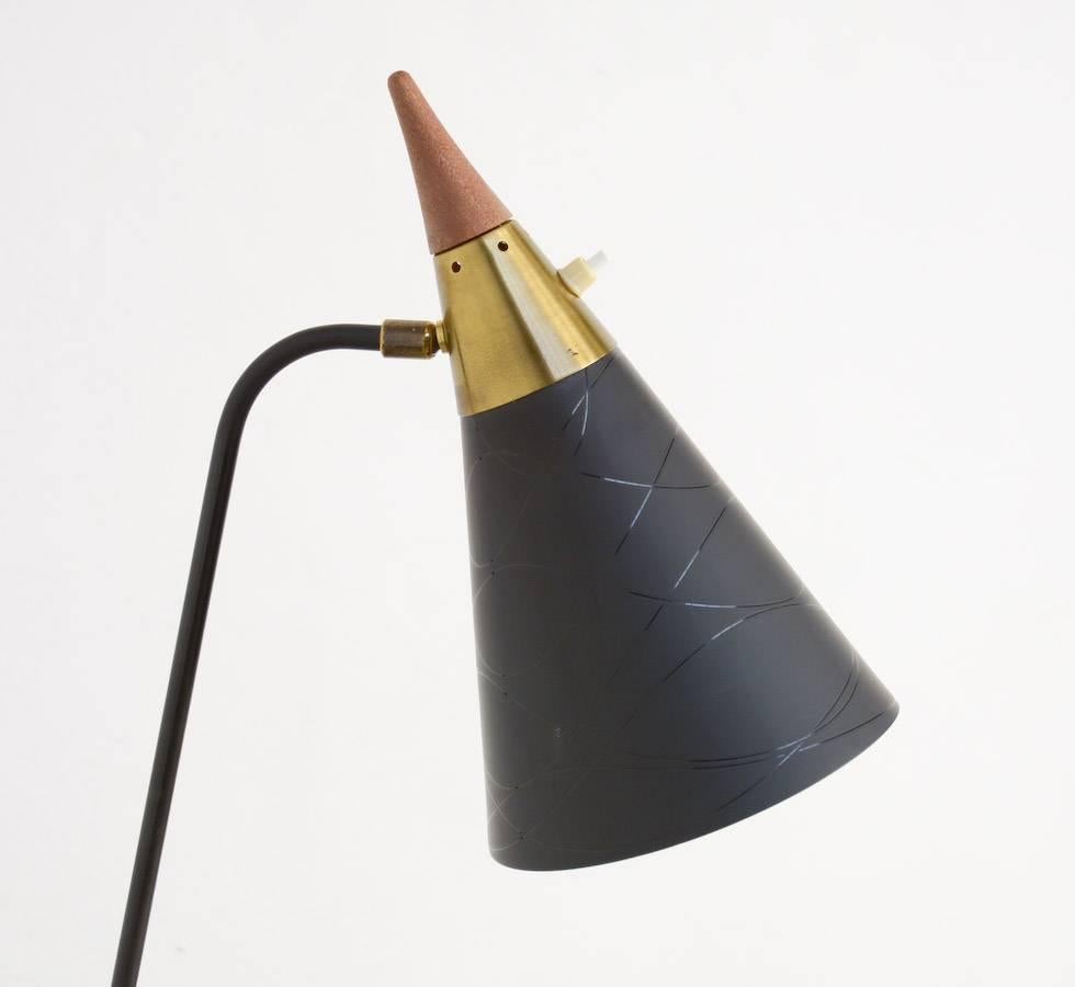 This unique 1950s floor lamp is really beautiful, probably Swedish.
The foot and stem are made of black lacquered metal and copper, the conical black metal shade is finished on the top with copper and teakwood. The shade is decorated with simple