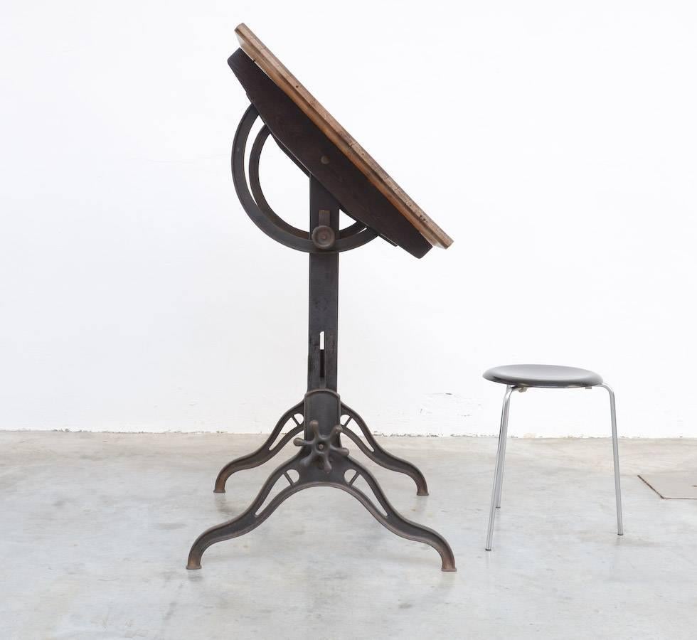 This old American drafting table can be dated in the early 20th century.
The base is made of black lacquered cast iron and wood.
The original pine wooden top has a nice patina.
This drafting table is still in very good Industrial condition, you