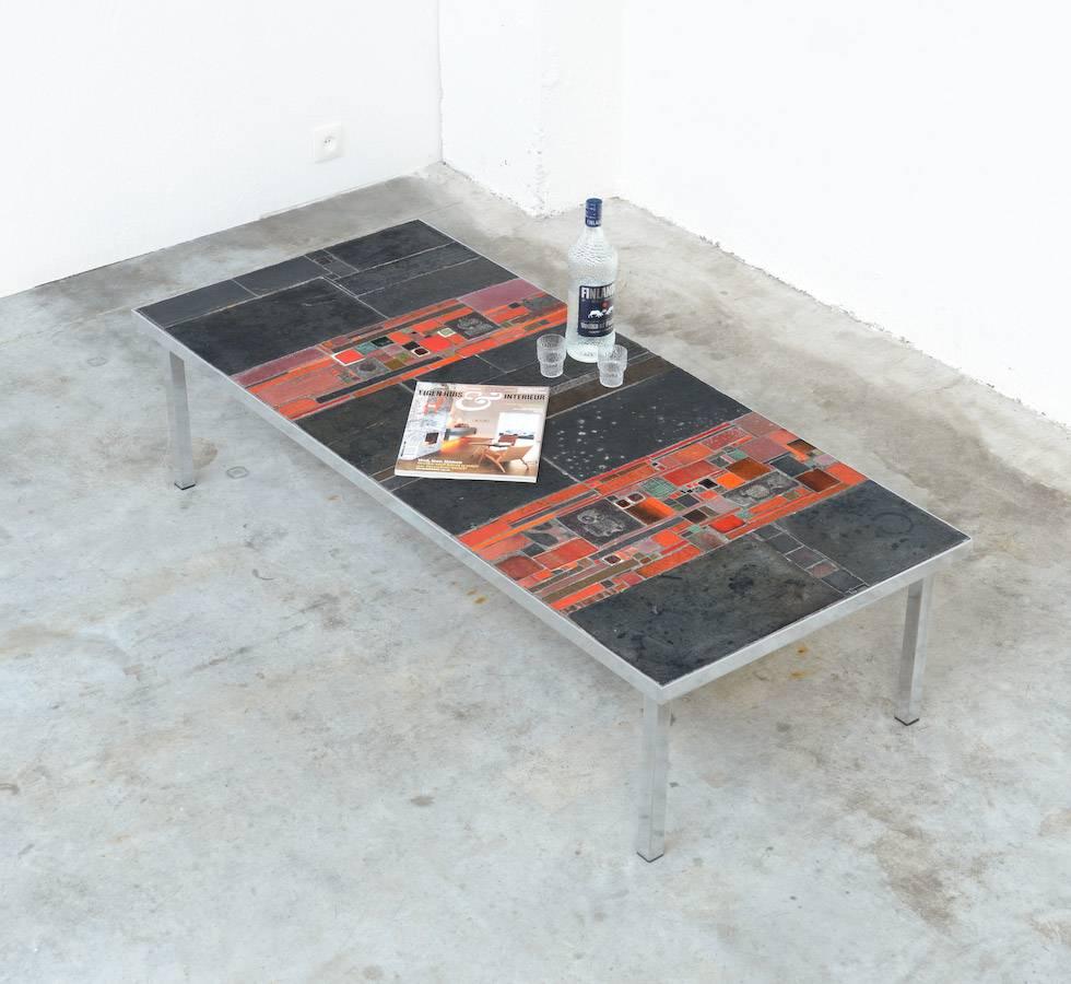 This early beautiful ceramic tile coffee table was designed and made by Pia Manu.
The table has a minimal chromed metal base and the top is a nice combination of different shades of red and black ceramic tiles. The tiles are really amazing, all