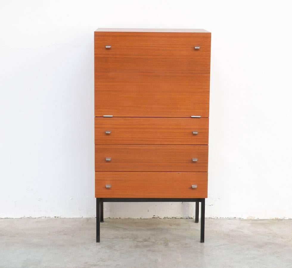This nice minimal cabinet is designed by Pierre Guariche for Meurop in the 1960s.
The cabinet is made of teak veneer on a black lacquered steel base. It can be used as a bar or writing cabinet.
This pure cabinet is an early production with small