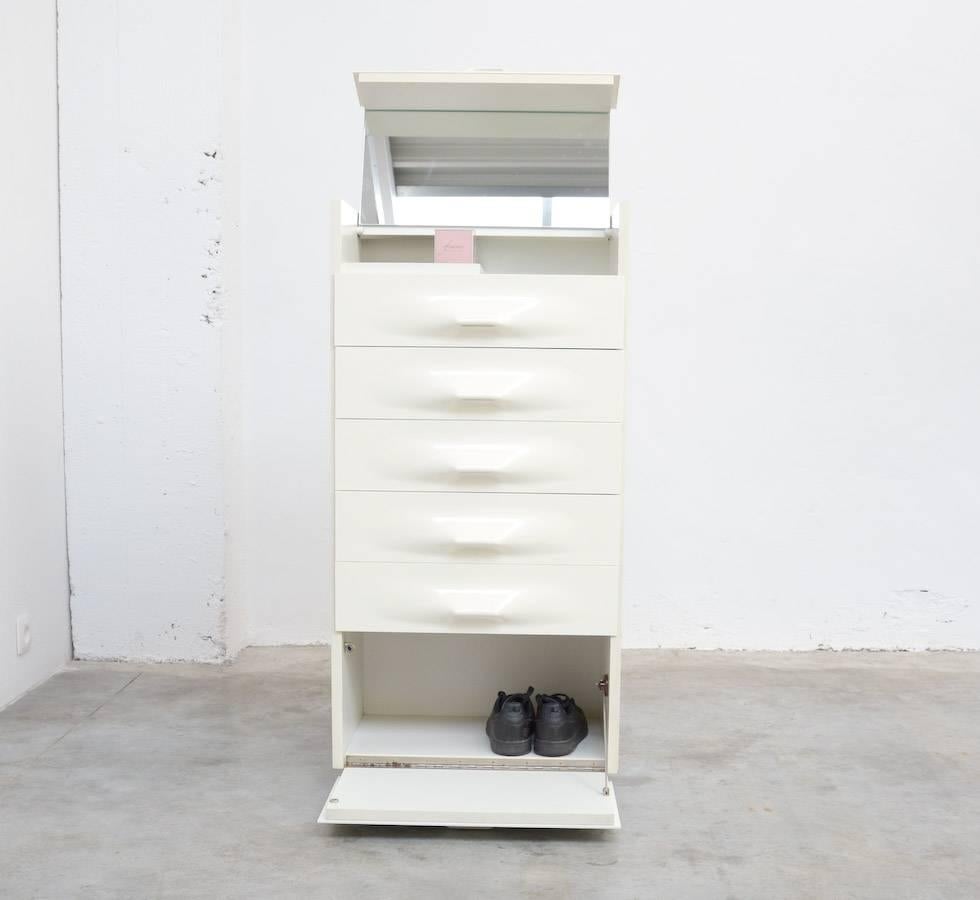 This super nice and compact dressing cabinet was designed by Raymond Loewy for Doubinsky Frères, France in 1969.
This exclusive and rare cabinet has a flip-top door with mirrored interior, three drawers and a drop-front storage for shoes. There is