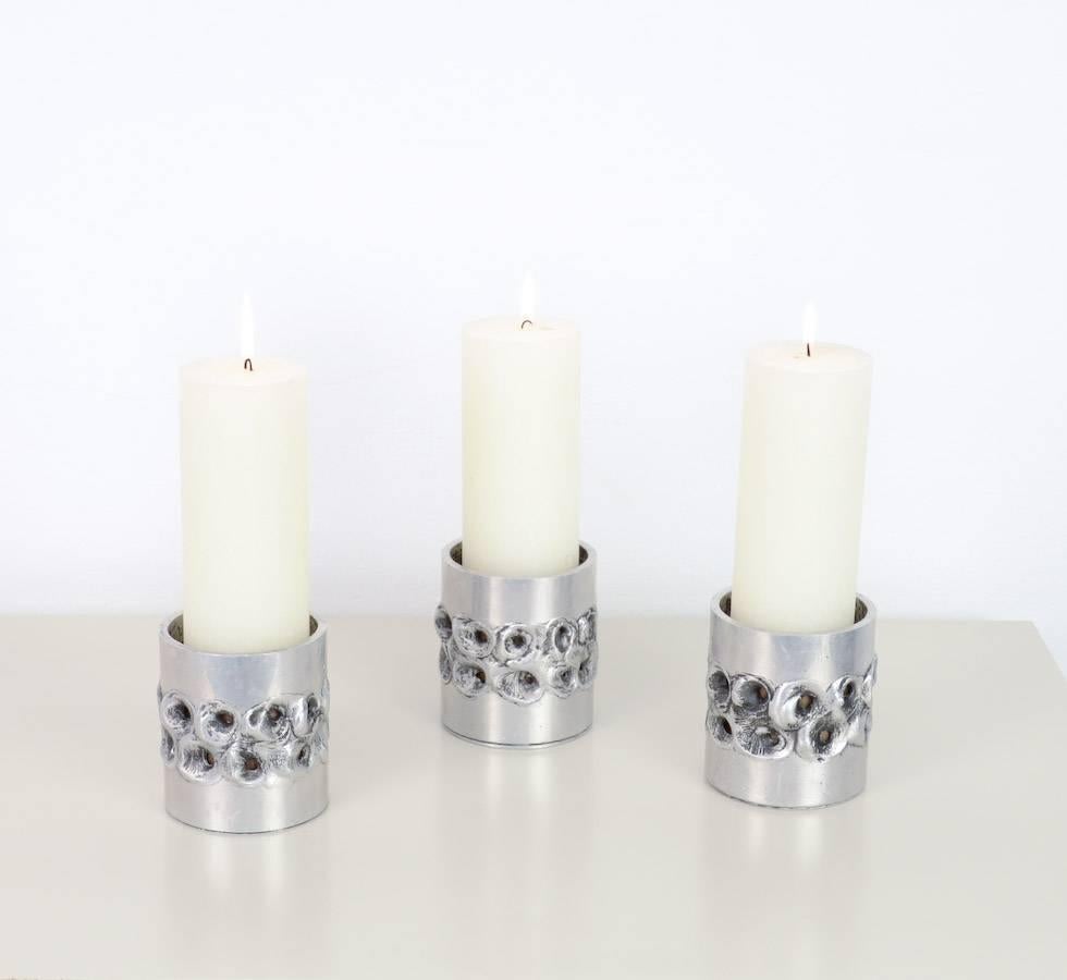 This nice set of Brutalist aluminum candle holders was designed by Luyckx W. for Aluclair Belgium in the 1970s.
These decorative candle holders are made with a special technique on aluminum to create a Brutalist effect.
The three candle holders