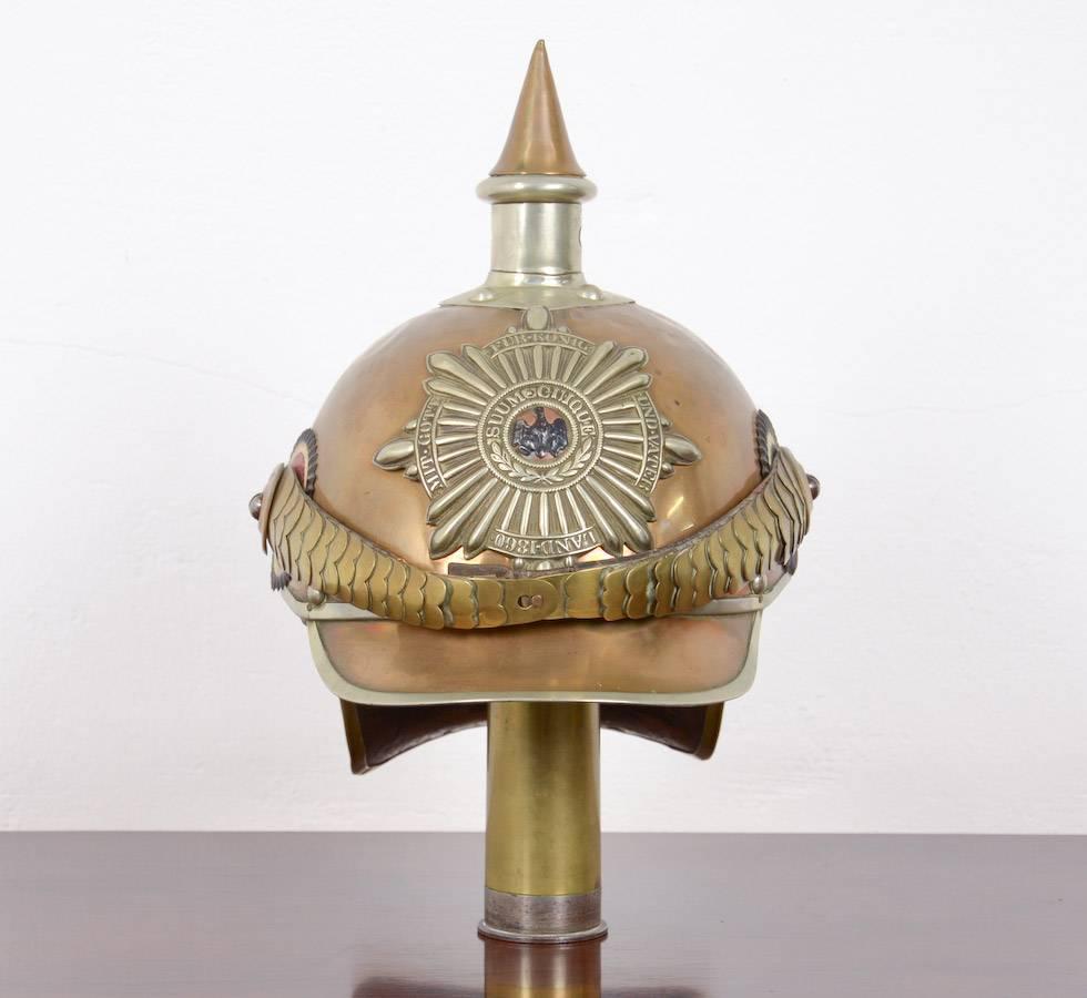 An outstanding helmet as worn by the personal guard of the German emperor Wilhelm II. One of the most elegant and well designed spike helmets (pickelhaubes) polished brass skull and trimmed in nickel, brass brim and “lobster tail”. Black/white/red,
