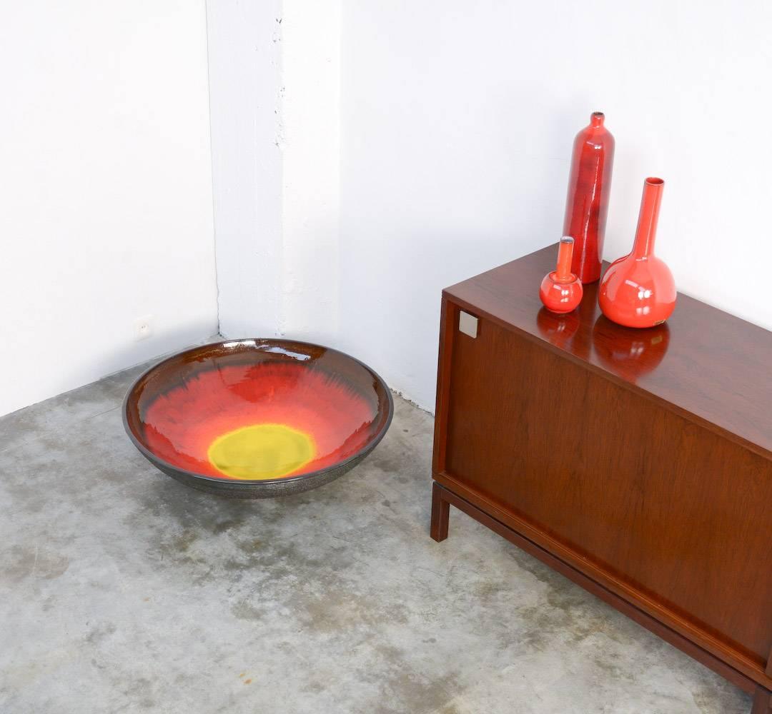 This very large bowl was designed by Rogier Vandeweghe for his workshop Amphora in the 1960s.
The size of this bowl is really unique, it just fitted in the ceramic oven.
The bright glaze in different shades of yellow, orange and red is