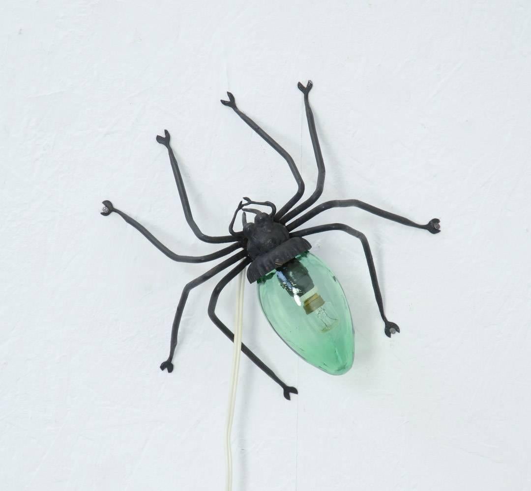 This unique spider lamp was made of hand-forged iron and green glass. It can be hung on the wall or placed on a table-top.
This special lamp will be an eye-catcher in your interior.
It is in very good condition and rewired. It can be dated in the