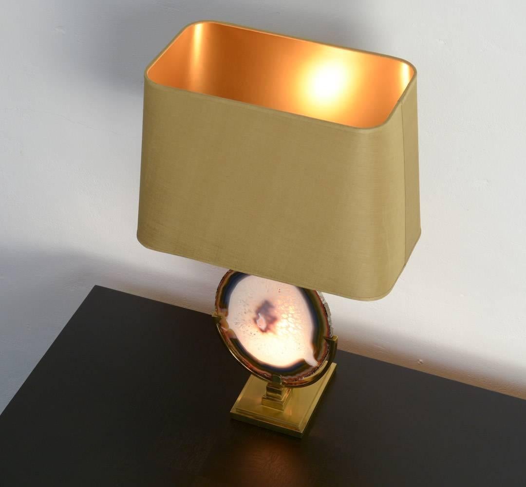 This magic table lamp was designed by Willy Daro in the 1970s.
The brass base holds the beautiful mineral agate stone. It is a unique piece. The agate stone is illuminated on the back.
This lamp is in very good condition with its original golden
