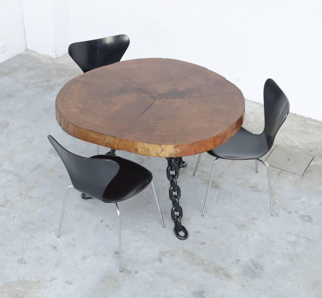 This impressive dining table can be dated in the 1940s or 1950s.
The three legs are made of heavy black lacquered metal chains.
The top is an amazing slice of a tree trunk.
It is an old dining table in very good original condition.
This