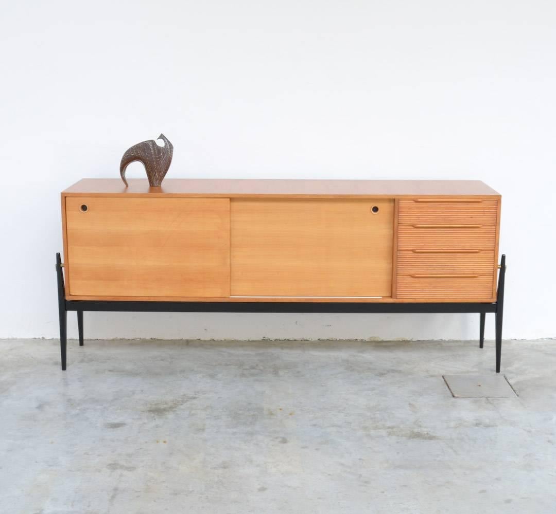 This elegant sideboard was made in Belgium in the 1950s.
The black lacquered wooden frame holds the birch wooden cabinet.
This low sideboard with two sliding doors and four drawers is a beautiful example of the Belgian furniture design of the
