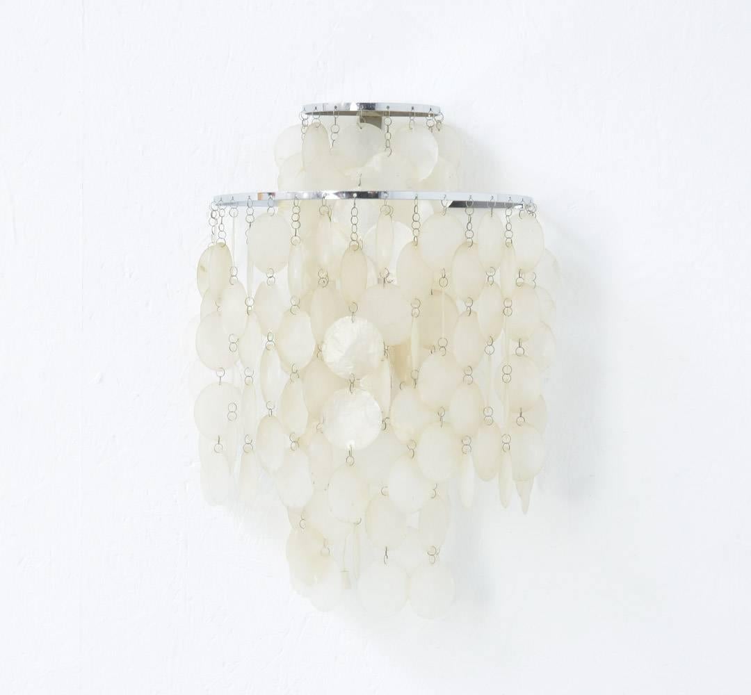 The Fun 2 WM is a wall lamp designed by Verner Panton in 1964 for Lueber, Switzerland.
The Fun lamp is a rare example of how Panton used natural materials for his creations.
This original lamp is complete with all metal chains and shell