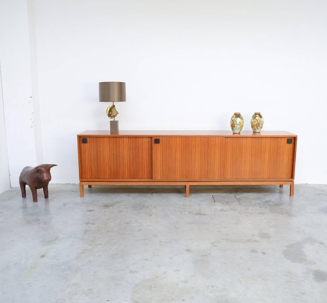 This extraordinary sideboard is a design of Alfred Hendrickx for Belform in the 1960s.
It is a minimal and pure piece of furniture made of high quality materials. The design of the wood veneer on the three sliding doors is amazing and creates on