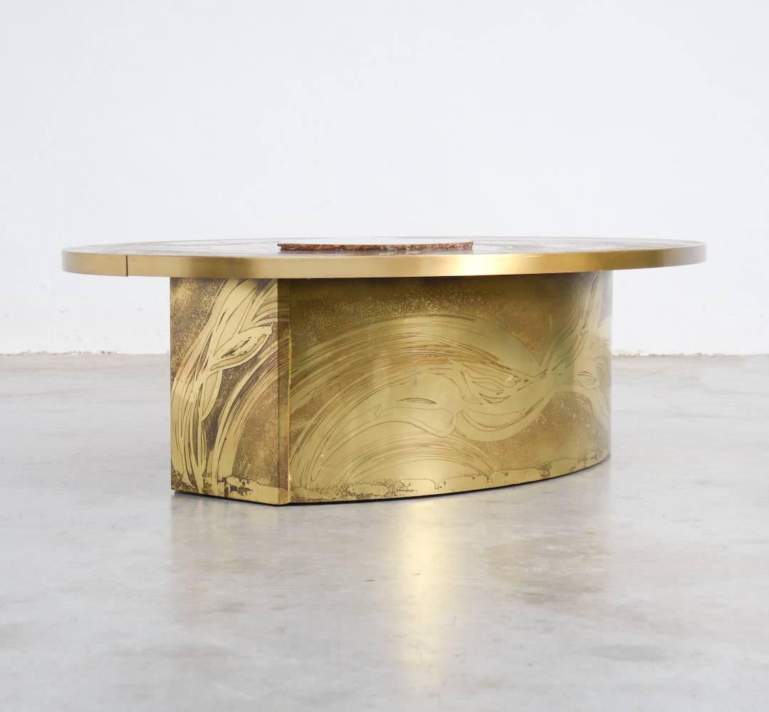This impressive coffee table is designed by the Belgian artist and designer Marc D’Haenens in the 1970s.
It is a unique piece of furniture with a brass oval top engraved and decorated with an agate stone.
This piece of art is signed on the top and