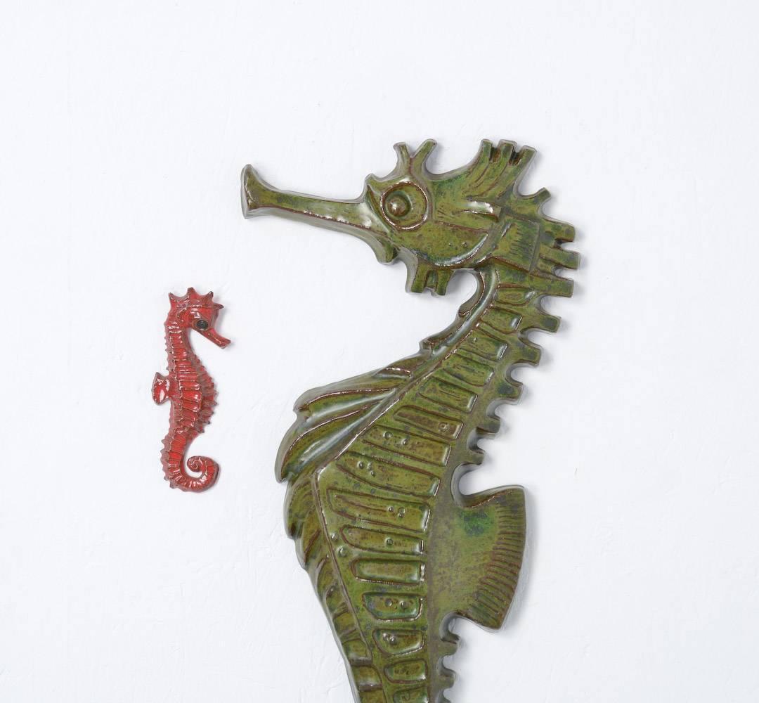 This set of three seahorse ceramic wall sculptures was made in the workshop of Amphora in the late 1960s.
The two small seahorses in red an white are marked.
The extra large green seahorse is not marked.
Seahorses always appeal to the