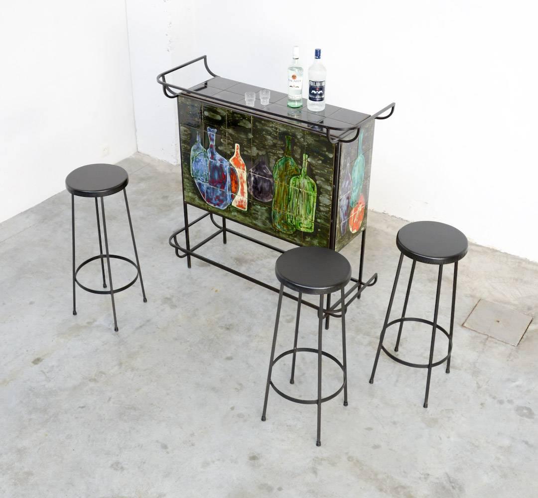 Let’s party!
This Mid-Century Modern bar is marked CAPR on the ceramic tiles.
The black lacquered metal framework is professionally made.
The bar is decorated with ceramic tiles that features nice shaped bottles. The composition and the use of color