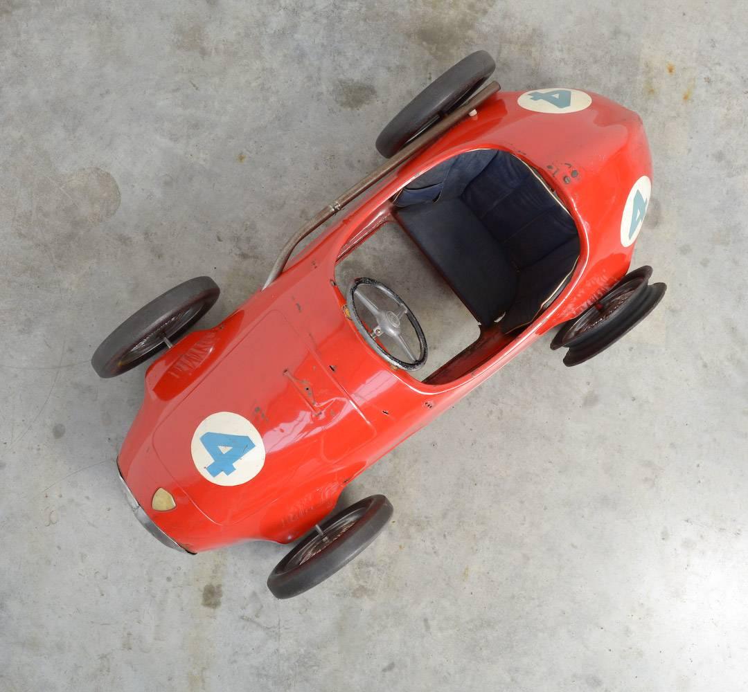 This old original Grand Prix Ferrari Pedal Car was made by Giordani in Italy and can be dated in the 1950s.
The car is rather damaged but still it is a very decorative piece: the red painted steel body, the number 4, the spoked wheels, the black