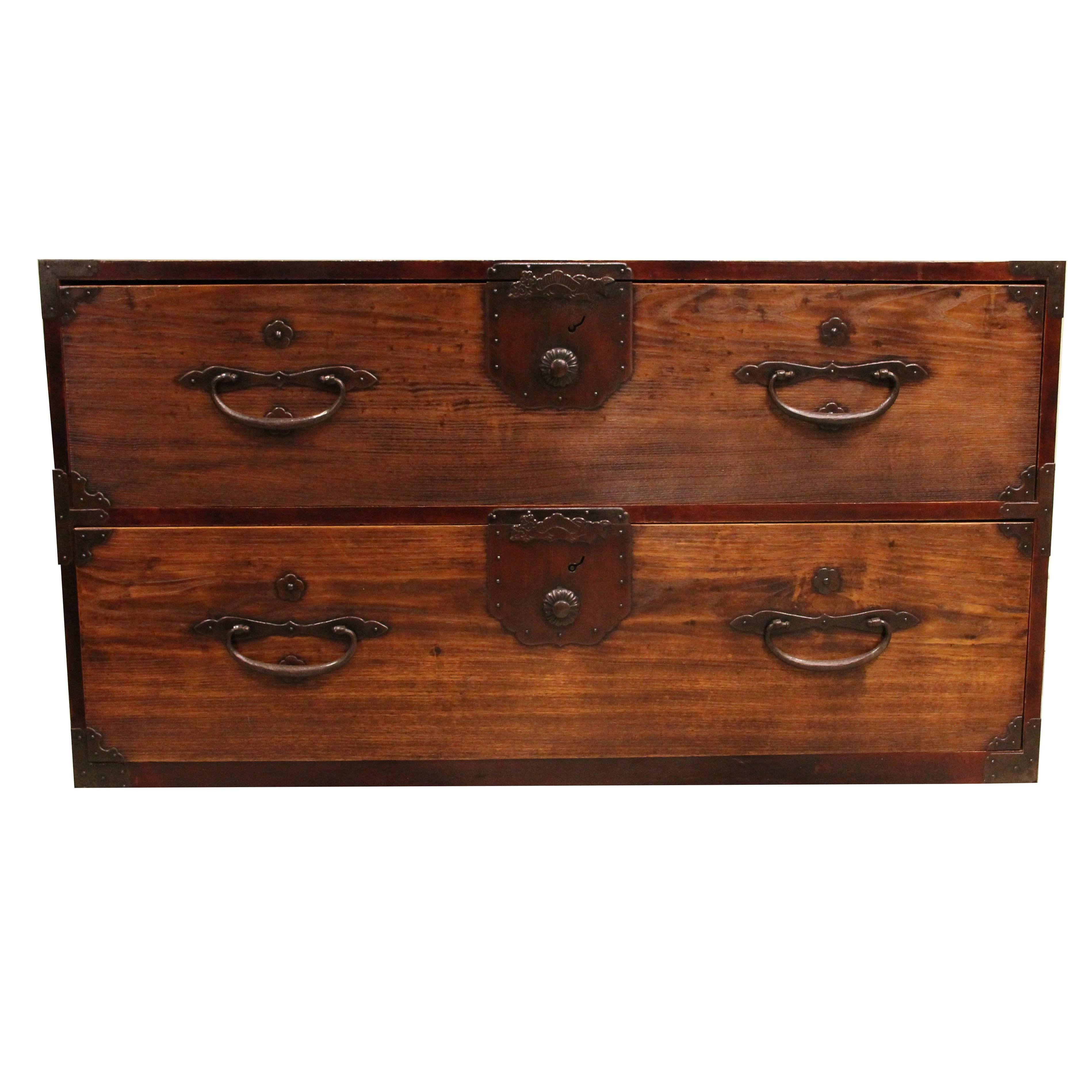 A Japanese clothing chest (isho-dansu).
The tansu with keyaki (zelkova) wood drawer and door fronts with rich translucent red lacquer finish and sugi (cryptomeria) wood case in two sections which latch together. The doors and drawers with finely
