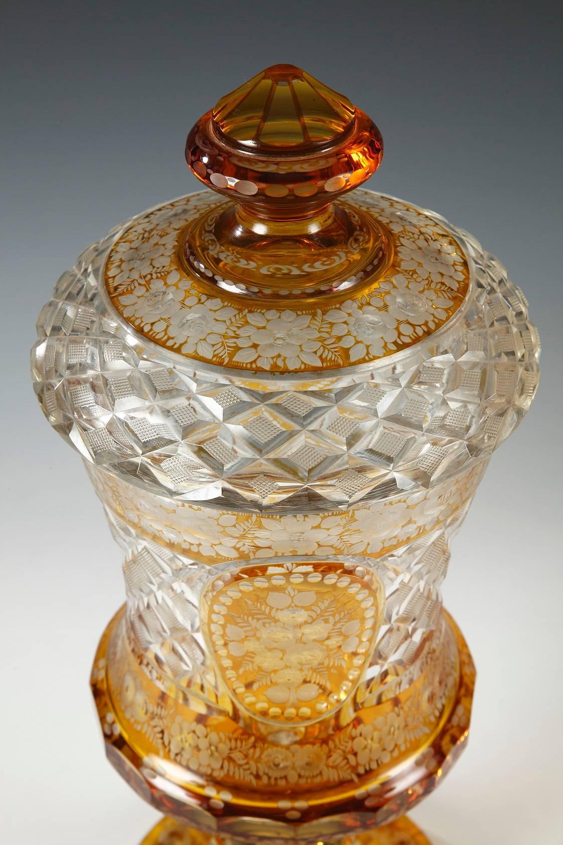 Ravishing pair of covered sweetmeat vases in Bohemian clear crystal suffused with amber, flared footed and slightly cup-shaped. The set is adorned with a rich wheel engraved decoration alternating between finely detailed floral patterns, pearl