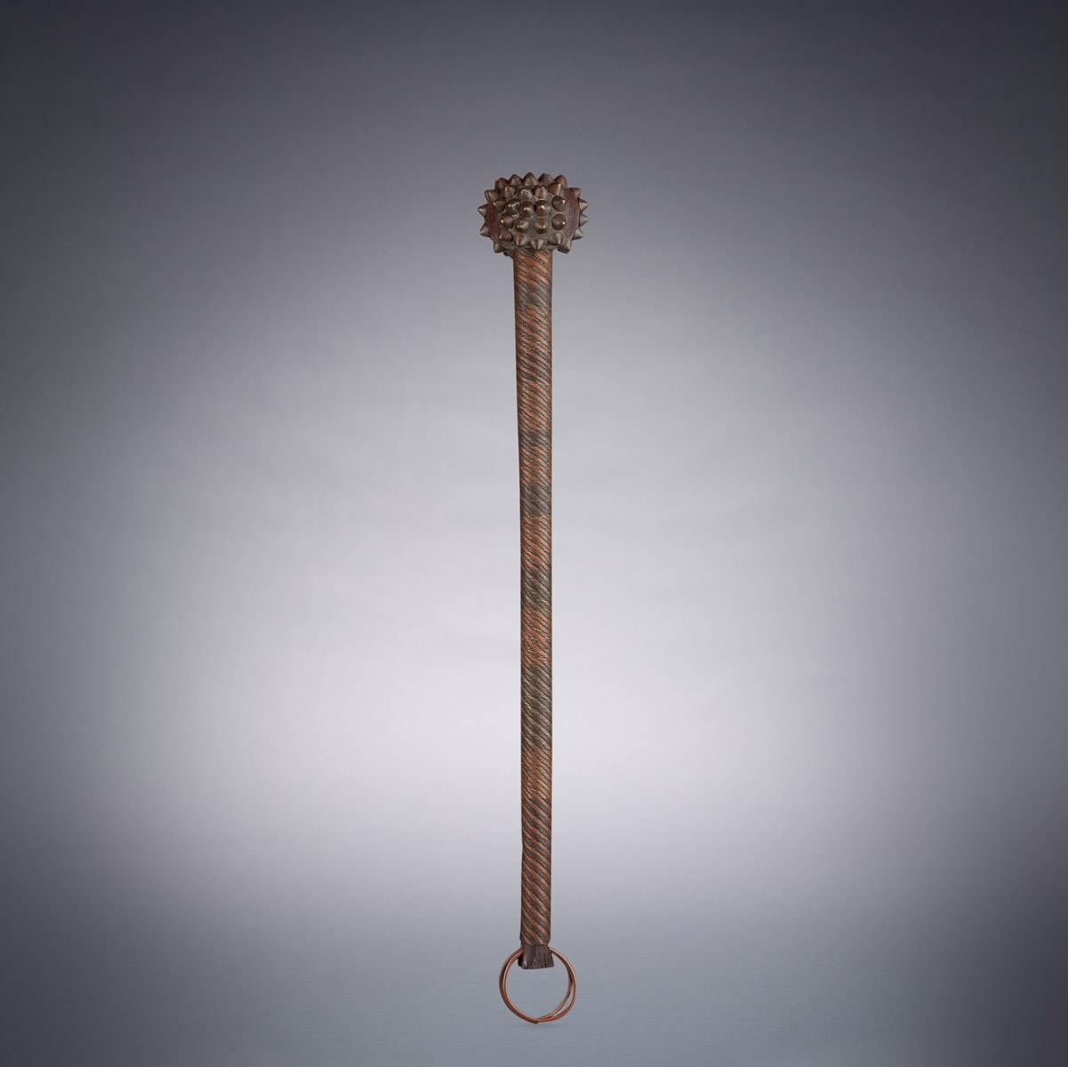 A South African knobkerrie designed to project power and intimidate enemies. This impressive piece features a shaft intricately decorated with brass and copper wirework and a spherical head adorned with brass studs. Condition is good, though a few