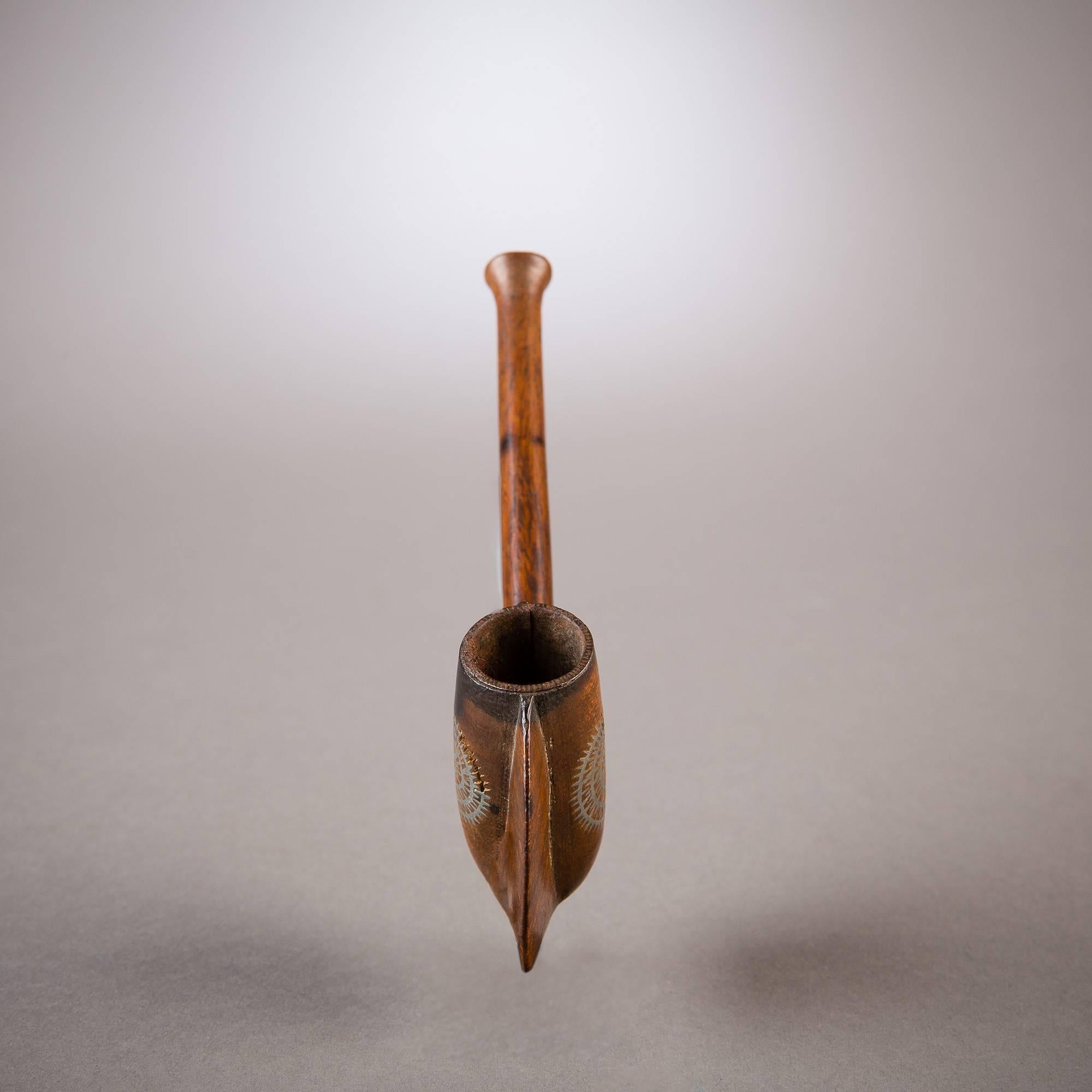 This disc-shaped pipe is a beautiful example of South African tobacco paraphernalia and an excellent example of the region's imaginative woodworking tradition. The stem merges seamlessly with the large, thin disc that describes a dramatic halo