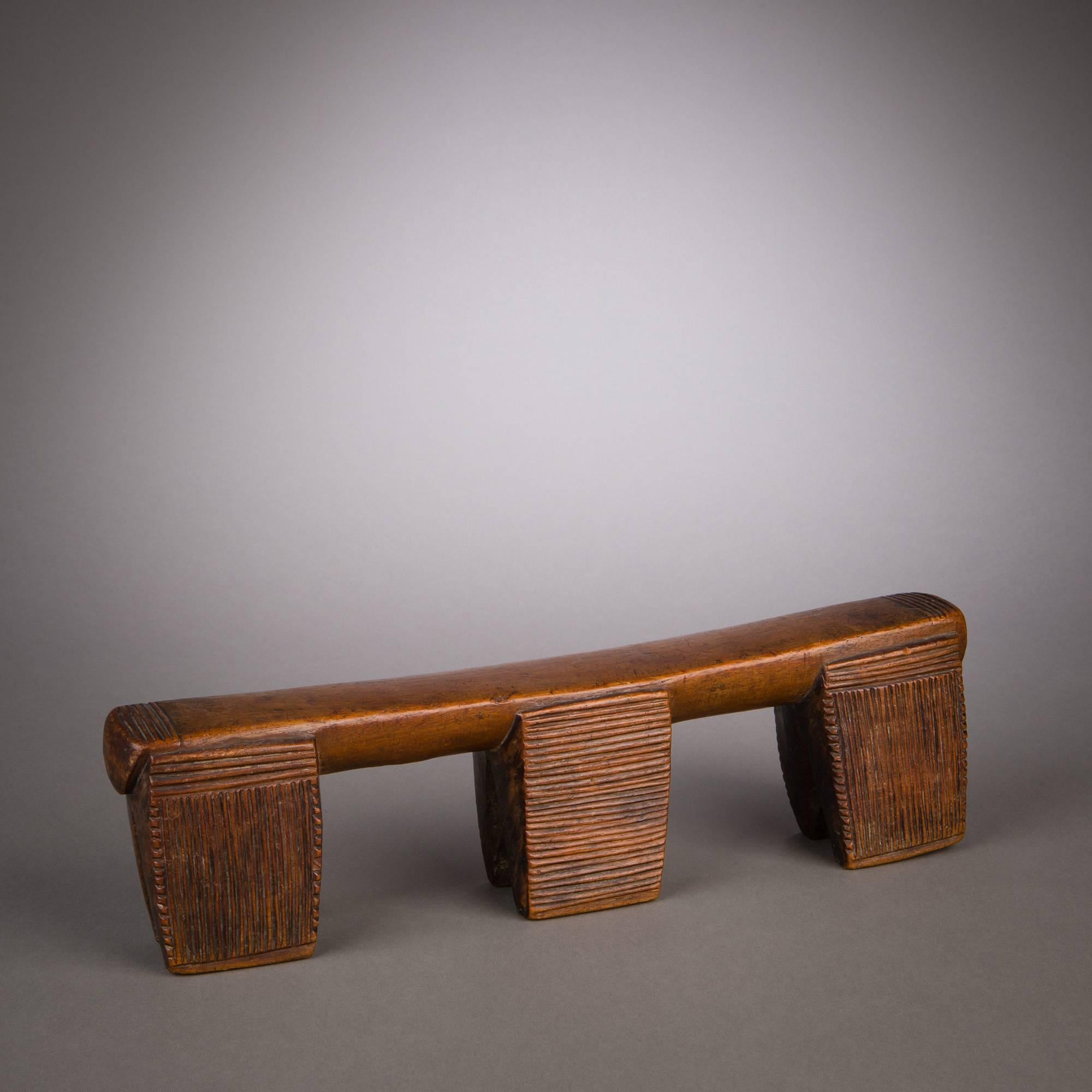A strong Zulu headrest of Classic, rectilinear design. Six legs support the rest, deployed in three close pairs that appear as blocks or panels when viewed frontally. The particular arrangement of elements in this rest's composition, with its strong