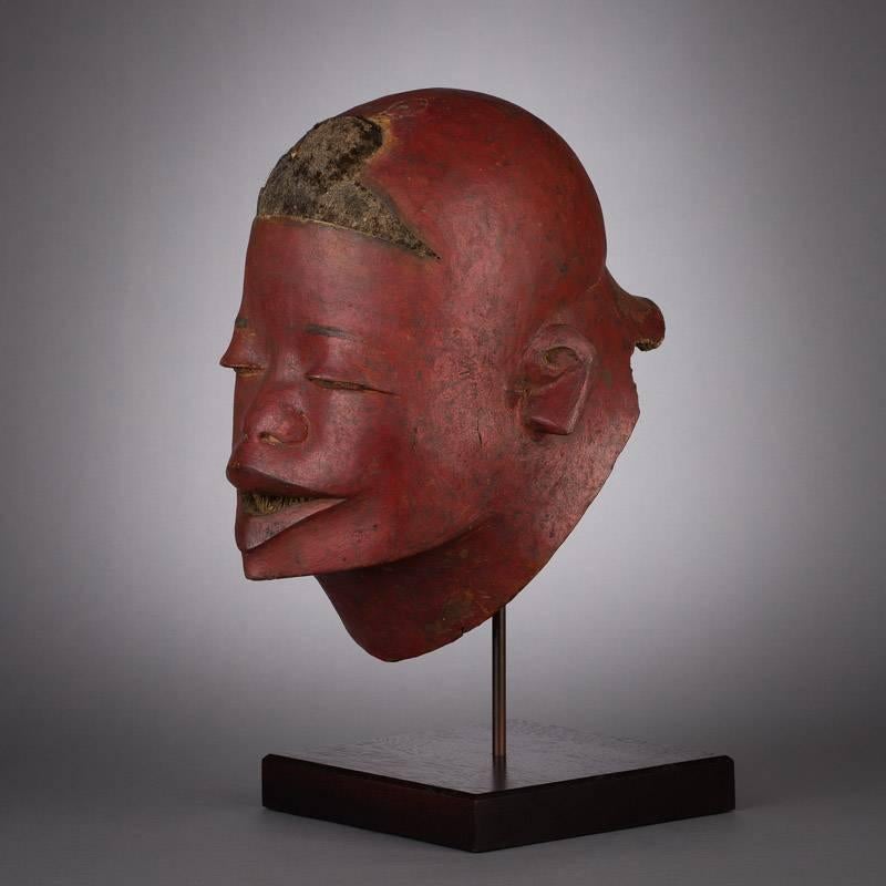 The powerful, ruddy hue of this helmet mask first arrests the eye, after which focus is drawn to its smooth and naturalistically rendered portrait. Masks of this type were originally used in initiation ceremonies and were worn by initiated boys, the