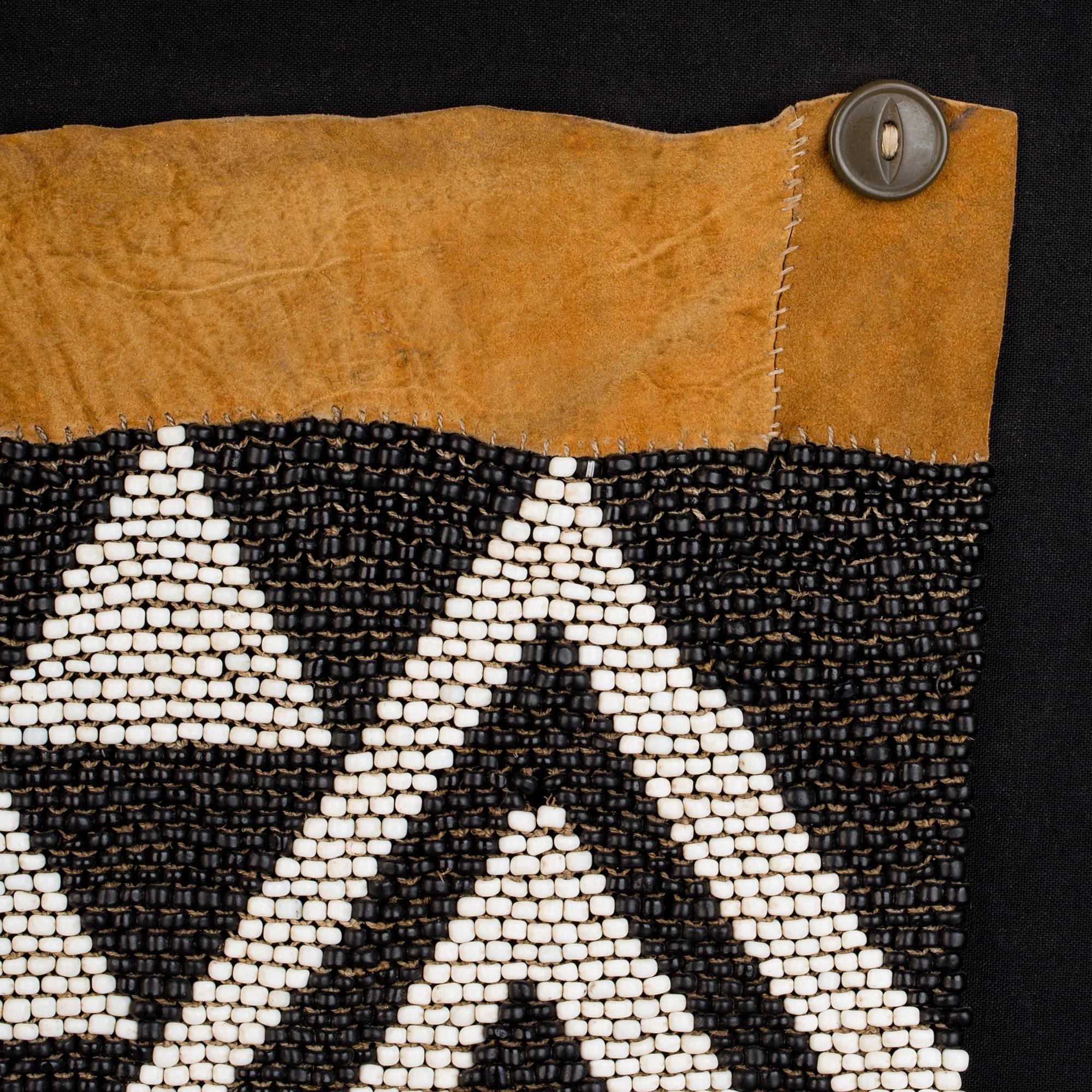 A stunning apron from Botswana, featuring strong geometric designs in dense, graphic sections that seem almost to evoke an abstract landscape with suggestions of mountain, sky, and shadow. Inverting the continuity of black and white at the equator