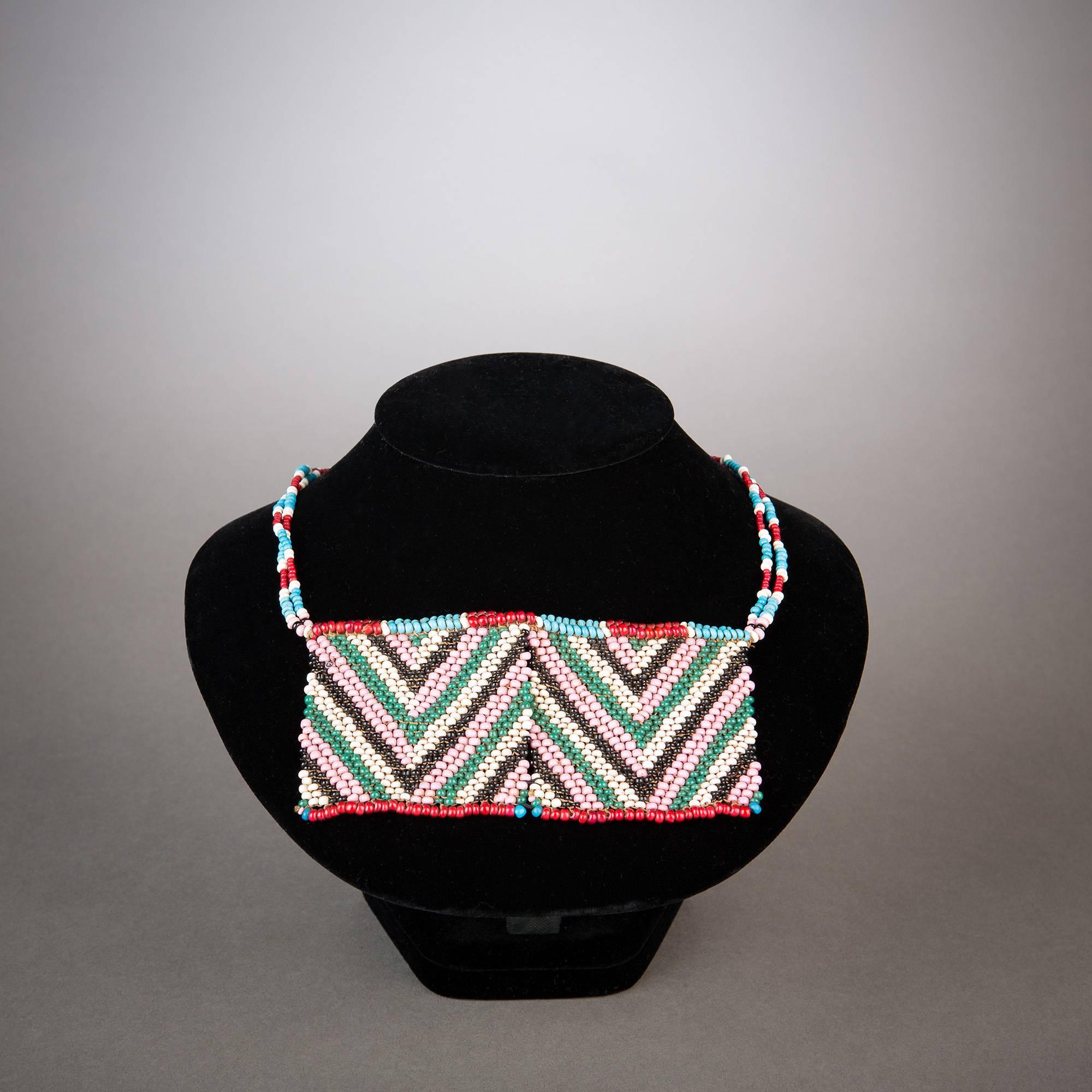 A gorgeous Zulu beaded panel necklace showing excellent preservation. Soft pink and mild green interplay beautifully with black and white in central chevrons lined by red and blue borders.

Panel necklaces of this type would have made up just one