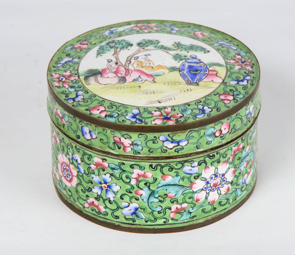 Canton enamel round box with a green background, decorated with flowers and multicolored foliage. The lid shows two figures in a landscape.
The interior is in blue enamel.

China - late 19th century
Height 5.5 cm - Diameter 9.5 cm