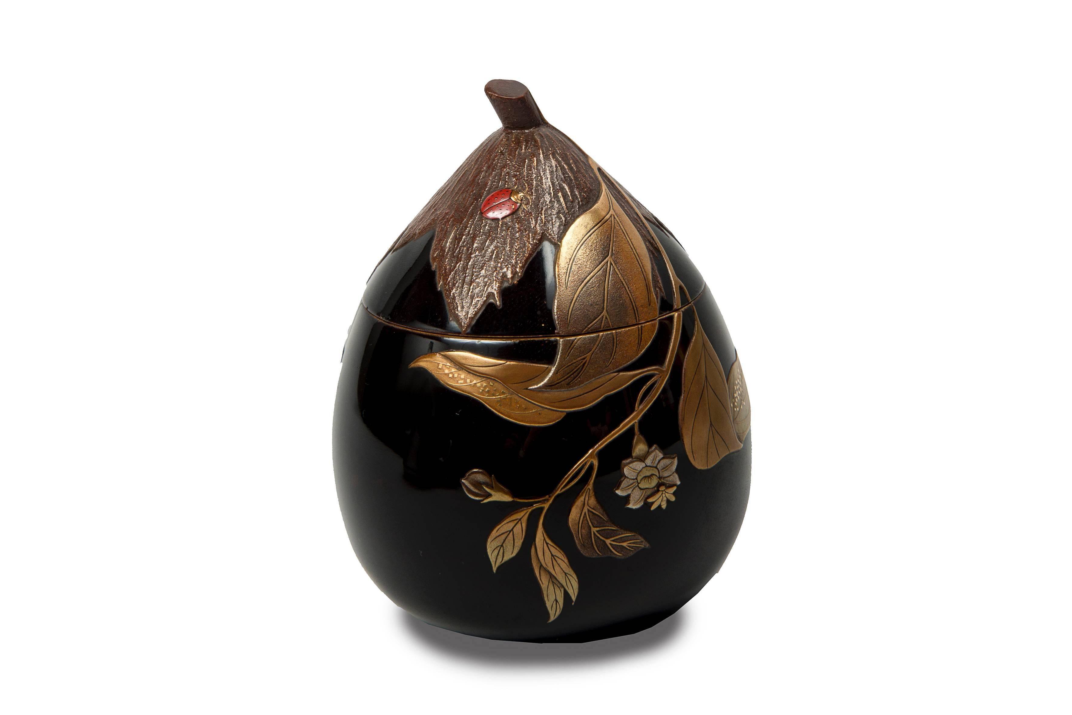Koro (incense burner) in the shape of persimmon in black lacquer with a gold, silver and red lacquer decor in hira maki-e of a ladybug on a leaf, a grasshopper and a bee in the middle of flowering branches.
Inside of the lid in nashi-ji lacquer.