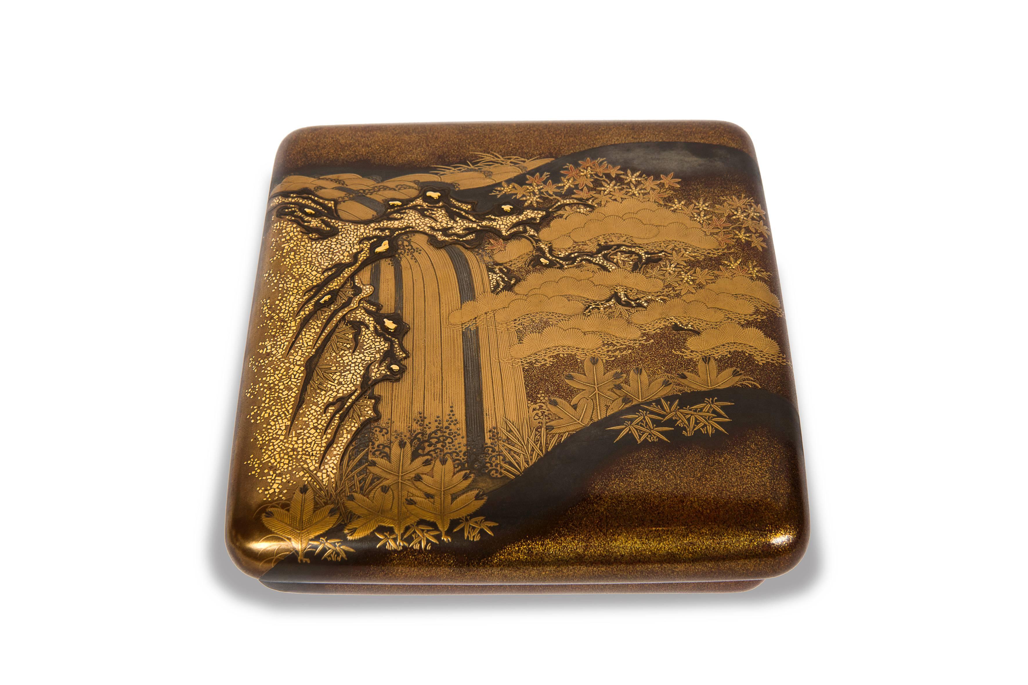 Exceptional suzuribako in hira maki-e, taka maki-e and hedatsu gold, silver and red lacquer of a bubbling waterfall amidst a pine forest.
The interior of the lid features five cranes, three in flight and two on the ground, in a landscape of pine