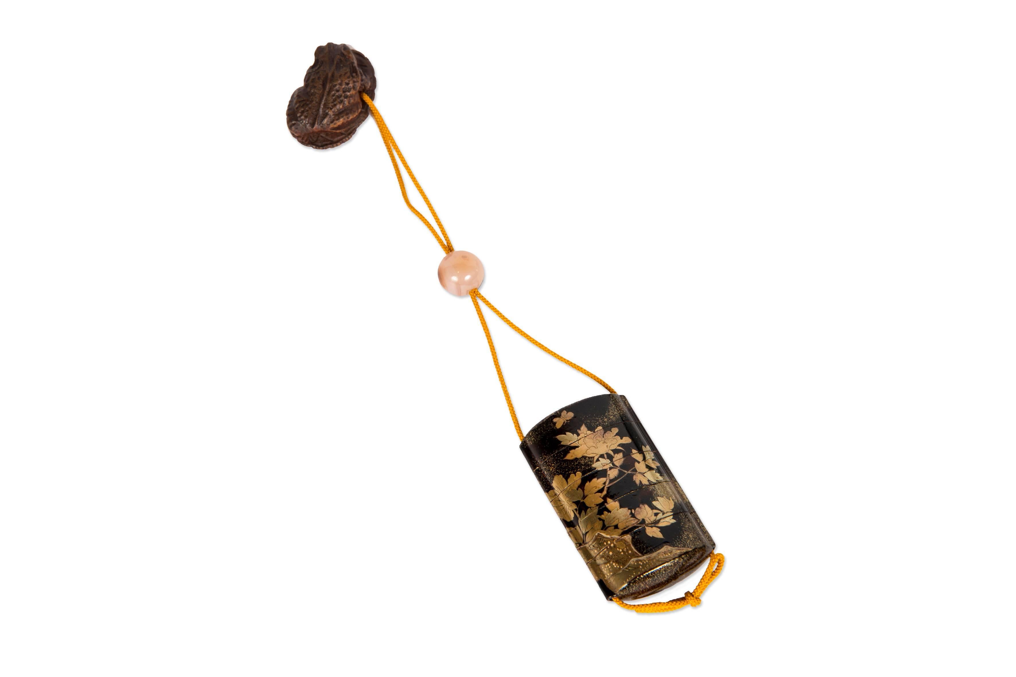 Inro are small divided boxes suspended from the belt which are a part of sagemono (suspended objects). Indeed, their use was developed to solve the lack of pocket in kimonos. 
This one is black lacquer with motives of leaves and flowers in gilded