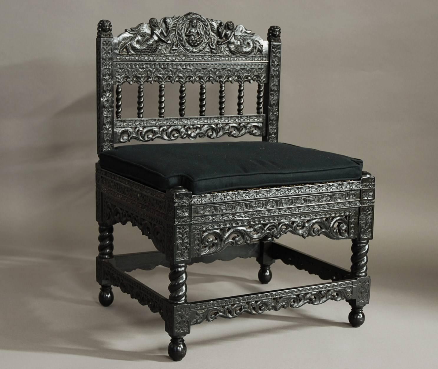 A superb quality late 17th century solid ebony low chair with intricate carving from The Coromandel Coast, India.

This chair, of museum quality, consists of a profusely carved back rail with a carved female figure to the centre surrounded by a