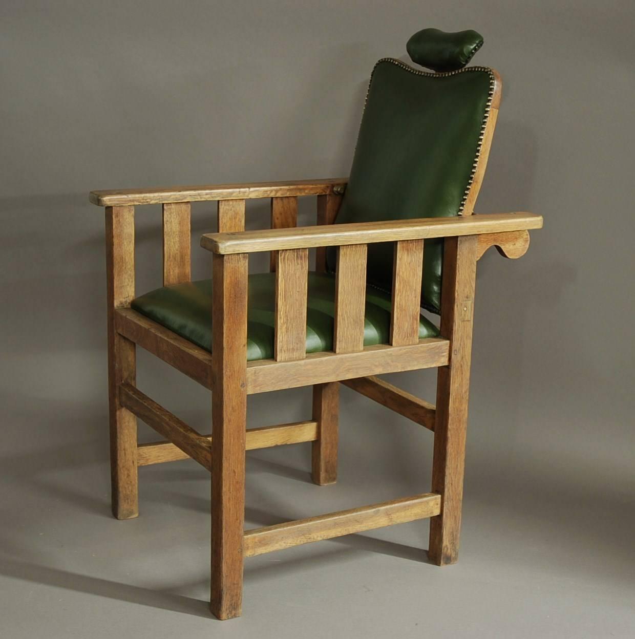 An early 20th century Arts & Crafts oak barber's chair with leather upholstery.

This chair consists of an oak frame of typical Arts & Crafts design with wooden slats to the sides.

The back and headrest are both adjustable and the green