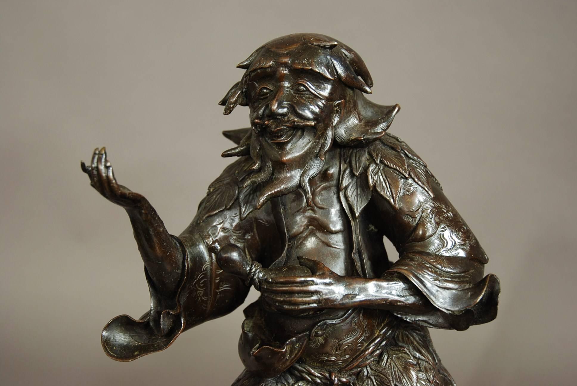 A late 19th century Chinese bronze of a wild man with claw feet.

This long haired, bearded man has the appearance of a wizened old man wearing torn and threadbare clothing with leaves. 

He is depicted standing on a naturalistic bronze base of