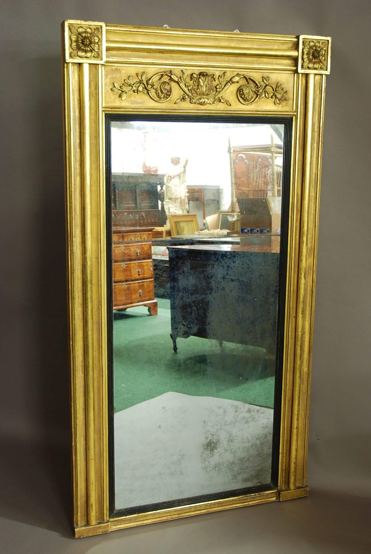 An early 19th century Regency wood and gesso gilt pier mirror of large proportions with original mirror plate.

The mirror consists of decorative corner blocks to each top corner of flower designs with a moulded edge to the top and the