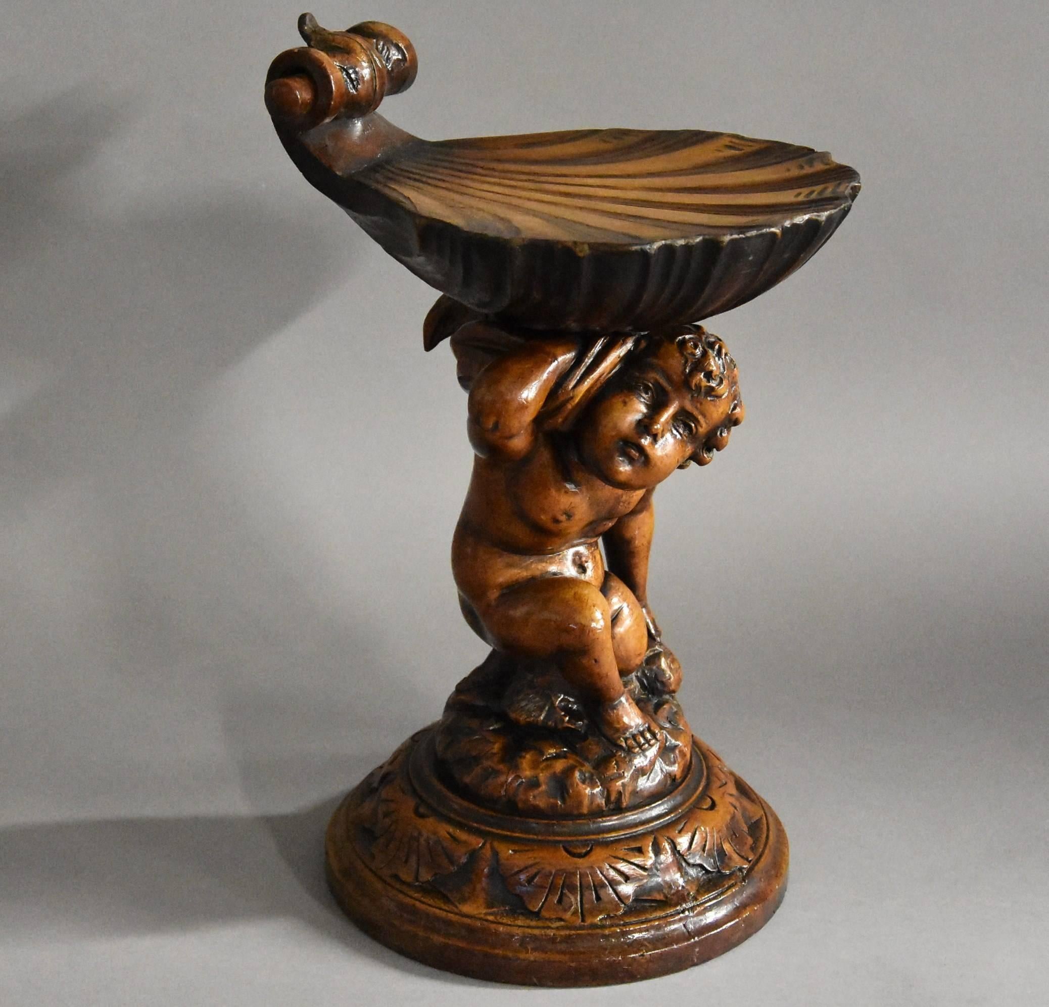 A highly decorative Venetian late 19th century pine putto and shell Grotto adjustable stool.

The stool consists of a carved scallop shell seat which is adjustable and revolving, this rests on the shoulders of the putto. 

This leads down to the