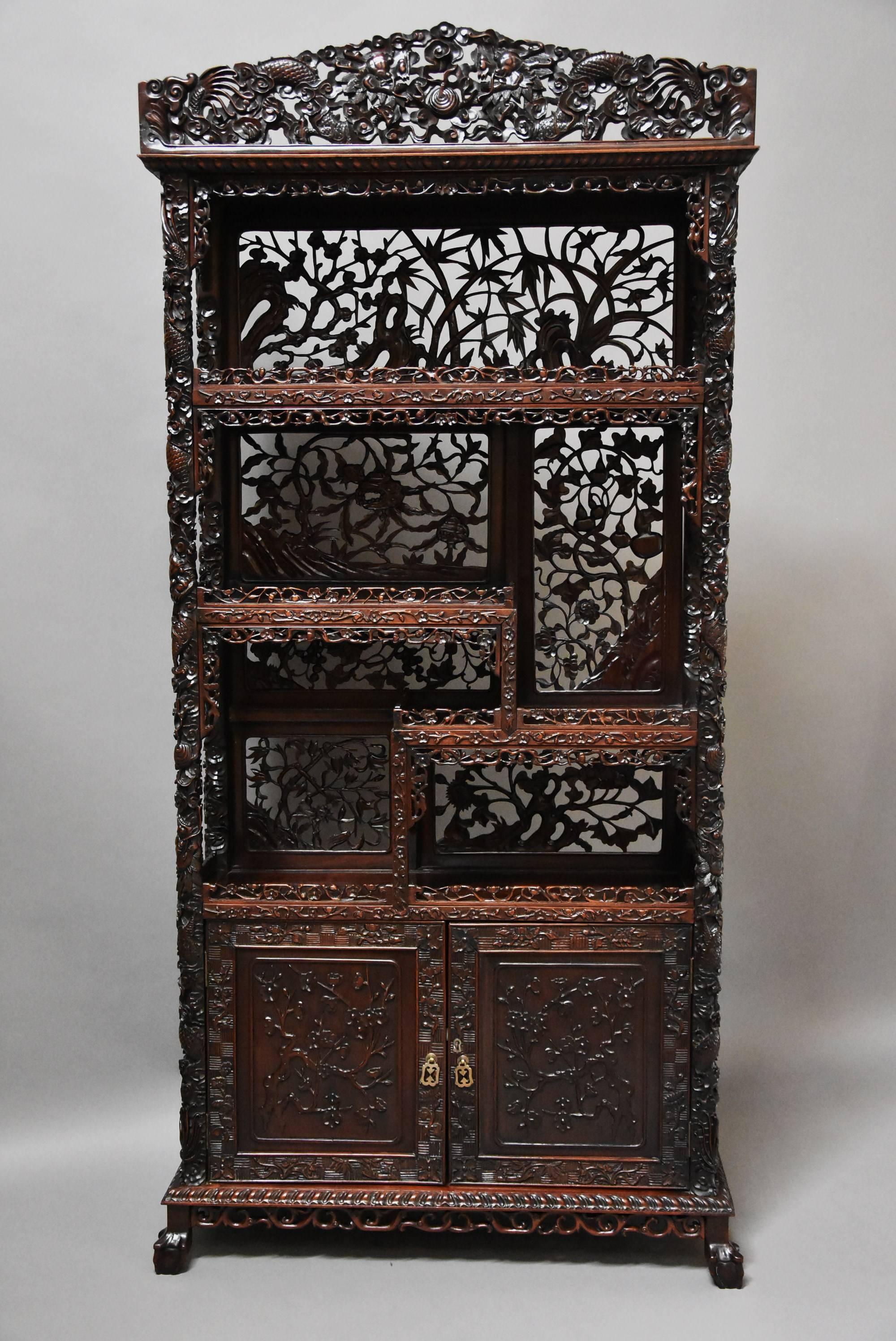 A late 19th century Chinese superb quality profusely carved padouk (or Chinese hardwood) display cabinet. 

This cabinet consists of a superbly carved and pierced shaped pediment to the top with carved Chinese symbols including dragons and exotic