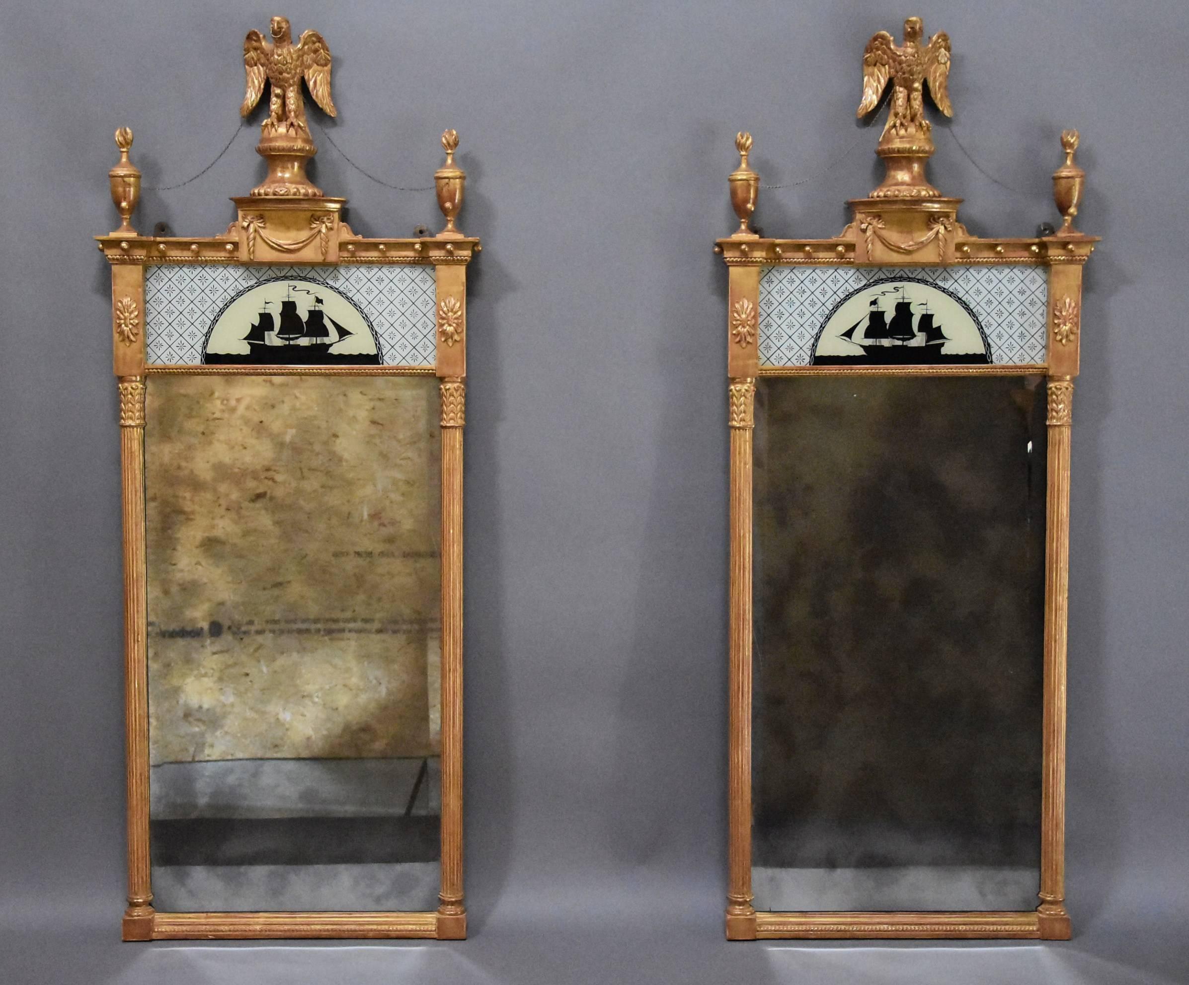 A superb pair of early 20th century carved giltwood pier mirrors in the Regency style.

This pair of mirrors consist of a finely carved eagle to the top supported by a carved dome topped pedestal with gadrooned edge leading down to a bow form