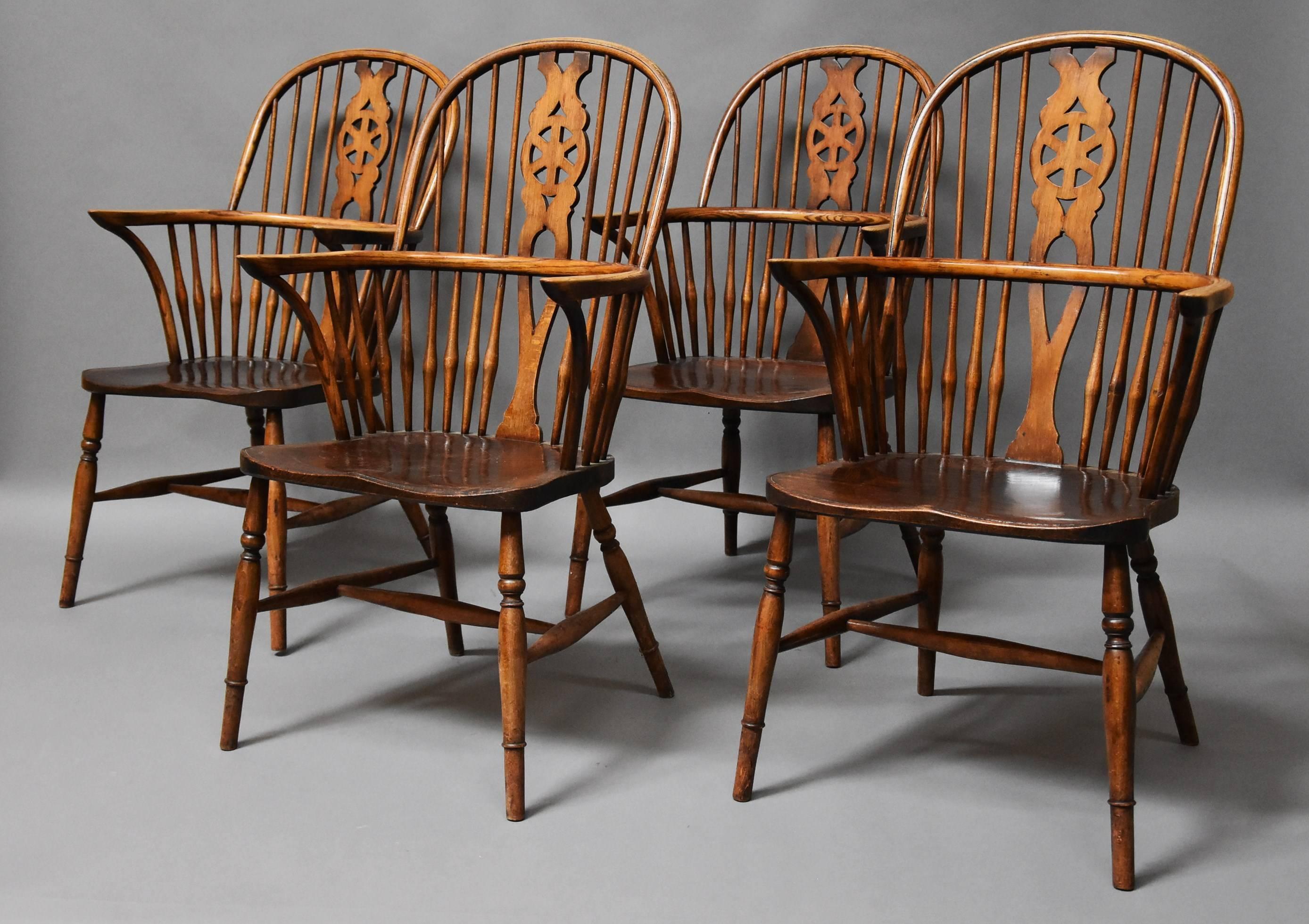 A set of four early 20th century ash and elm wheelback Windsor chairs.

These chairs consist of a hoop back leading down to a central pierced splat with wheel design with four turned spindles to either side.

This leads down to the arms and the