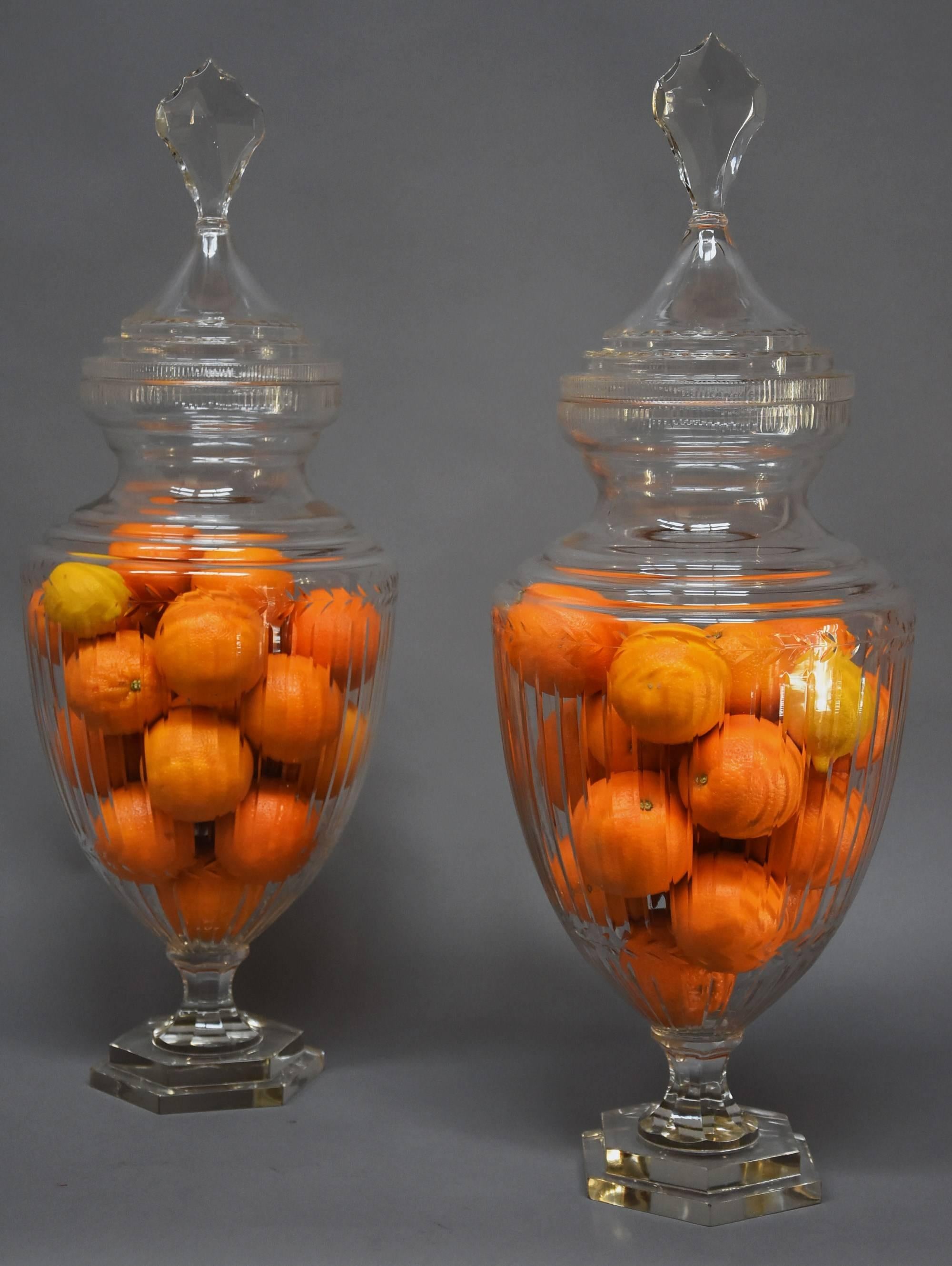 A highly decorative large pair of Edwardian cut-glass lidded display jars or possibly apothecary jars.

These impressive lidded jars consist of a large glass lid (or cover) with finial with cut-glass decoration, the rim below also having cut-glass