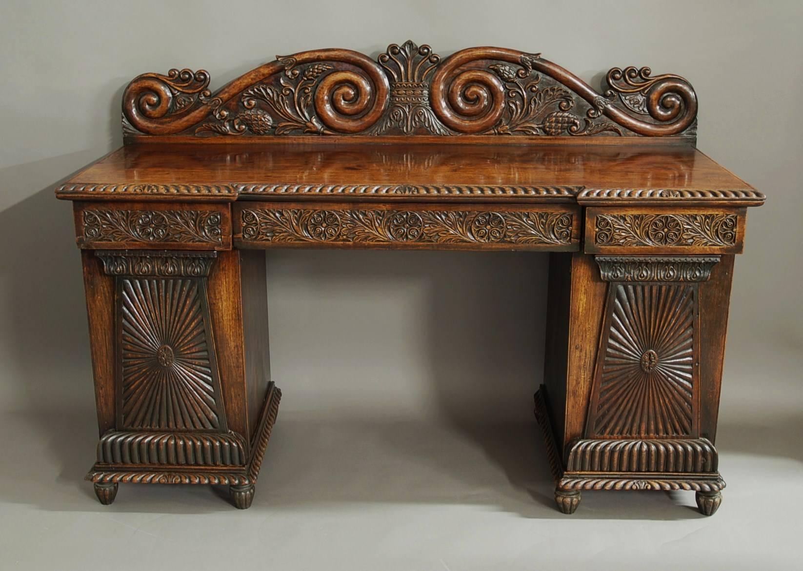 Superb quality mid 19th century Anglo Indian padouk inverted breakfront pedestal sideboard of superb patina (colour) from Bombay or Southern India.

This sideboard consists of a finely carved back-splash with central anthemion design with scrolling