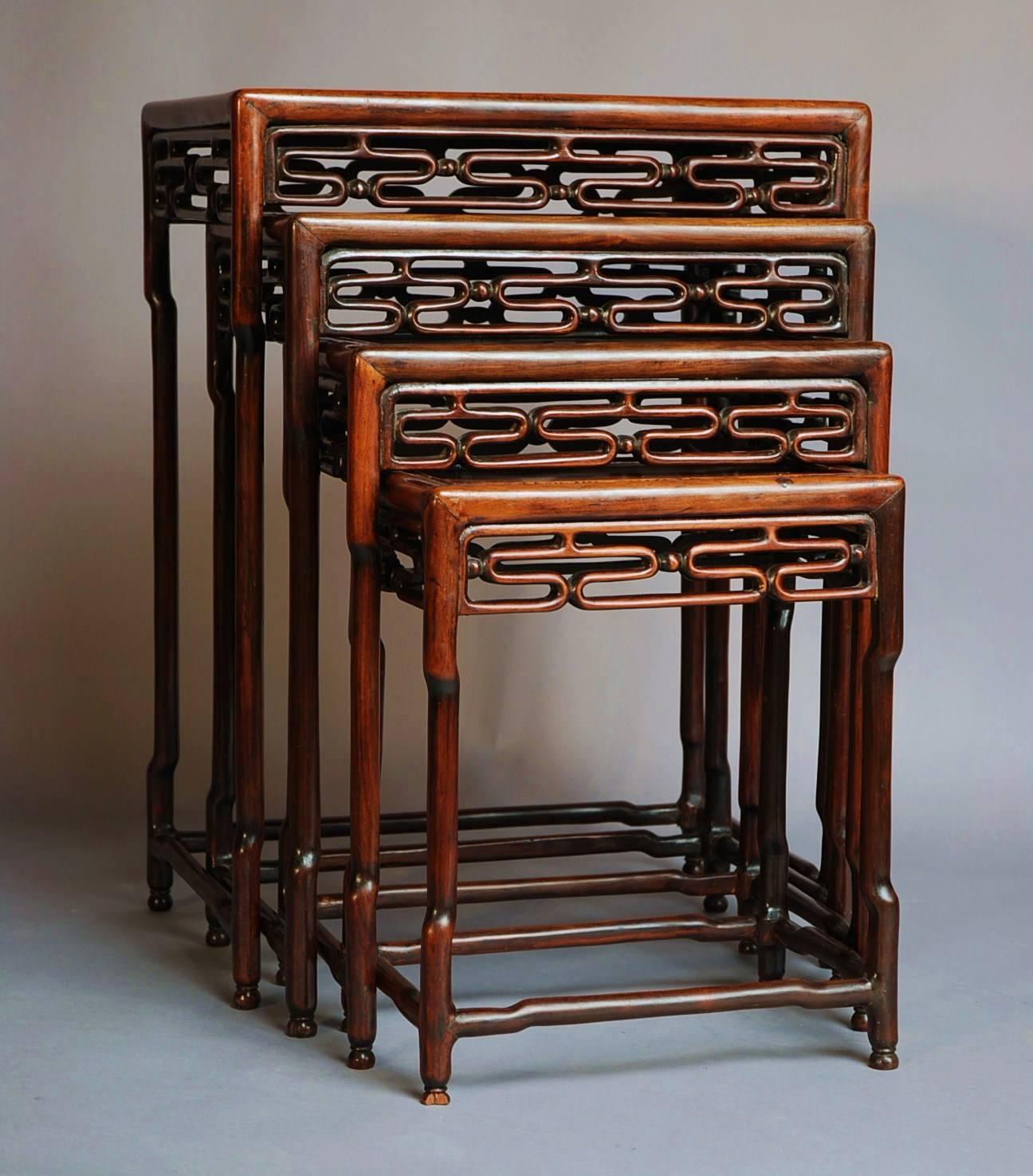 A late 19th century set of four graduated 'Quartetto' Chinese hardwood tables of good patina (color).

Each table consists of hardwood top with a carved geometric design frieze leading down to the legs being of bamboo design and joined by bamboo