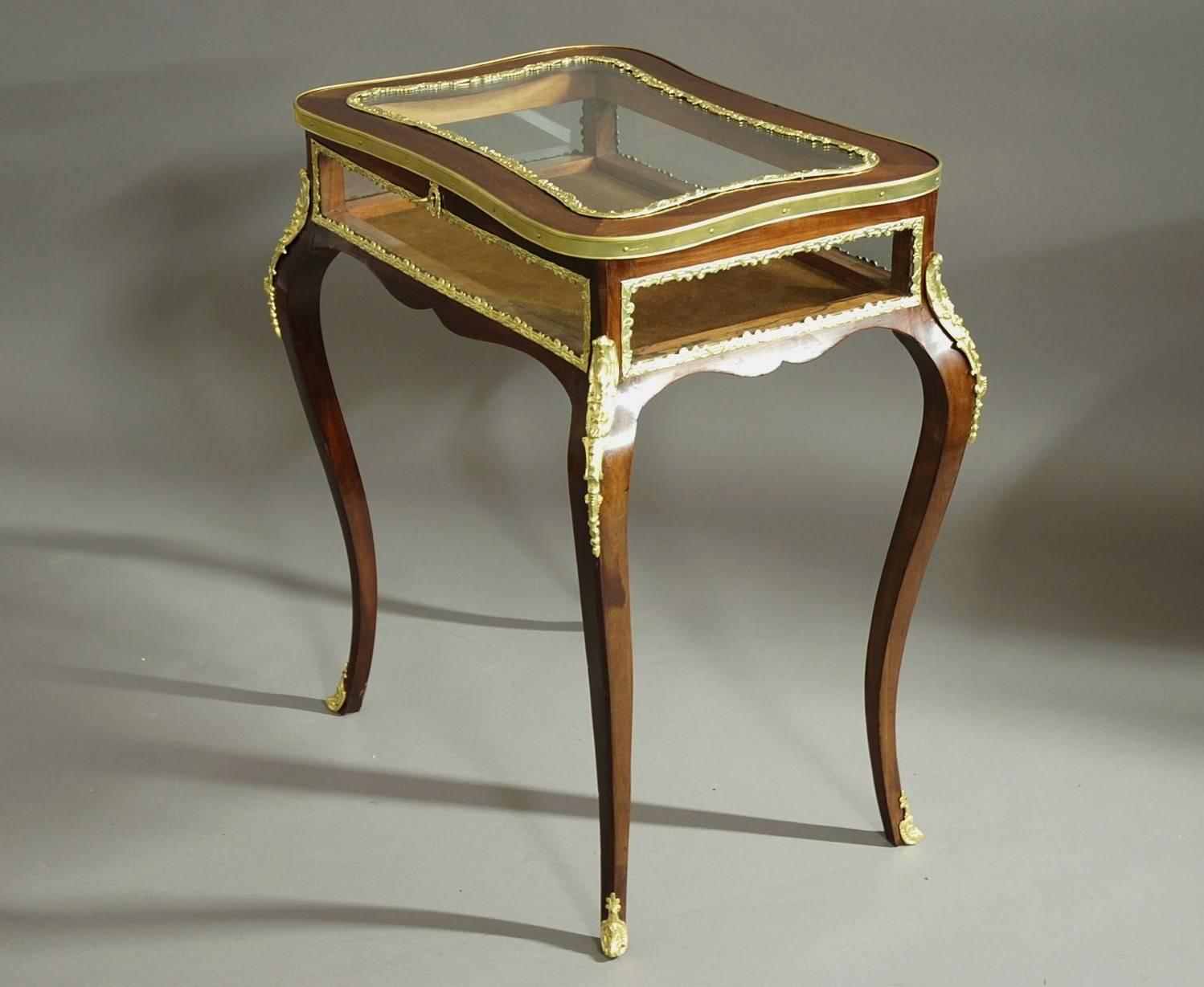 A French, late 19th century, mahogany freestanding bijouterie table of small proportions with key. 

This highly decorative table consists of a shaped top, the glass with a decorative ormolu moulding surrounding it with a reeded ormolu moulding